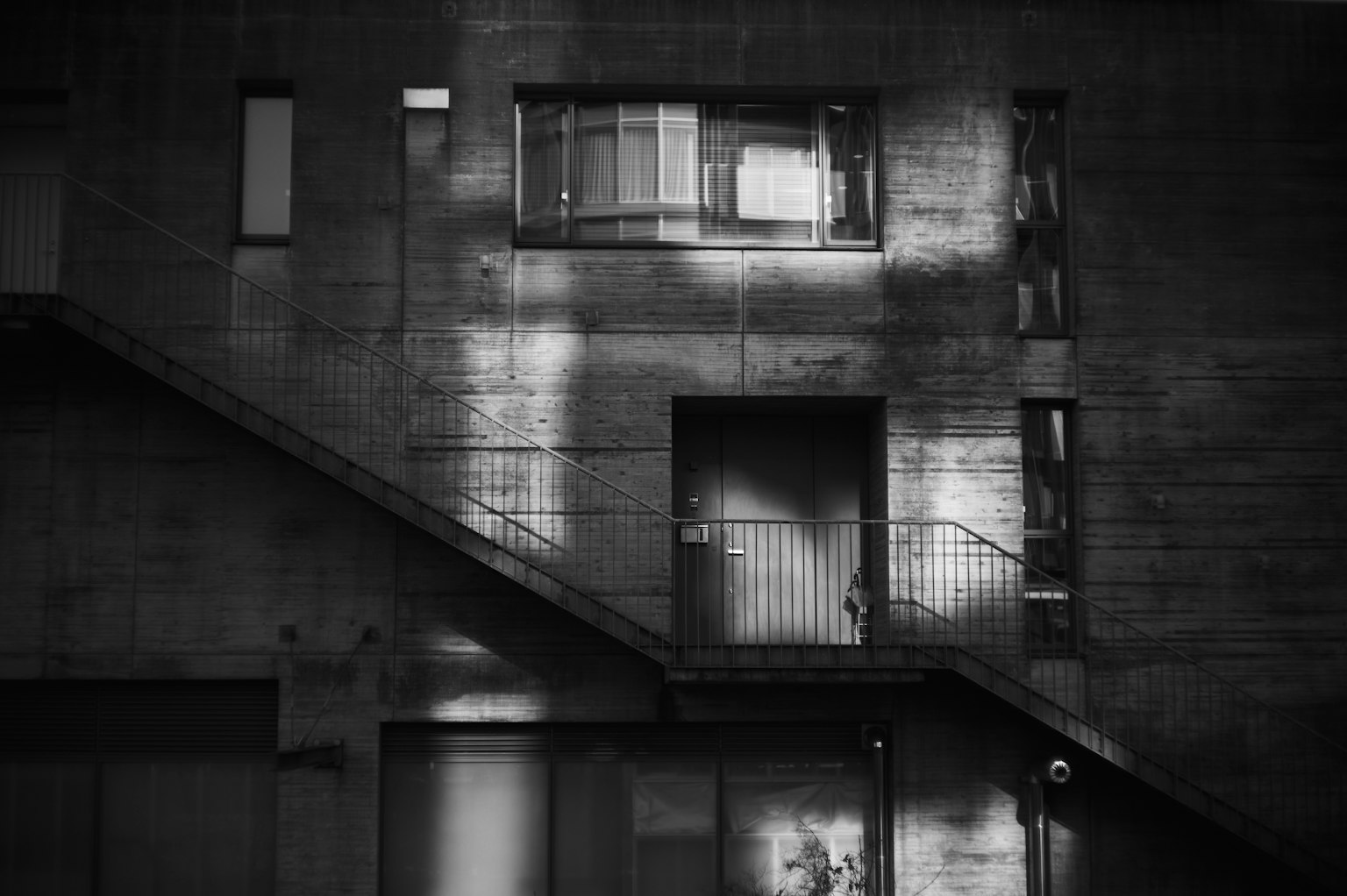Extérieur d'un bâtiment avec des murs en béton et un escalier éclairé par la lumière