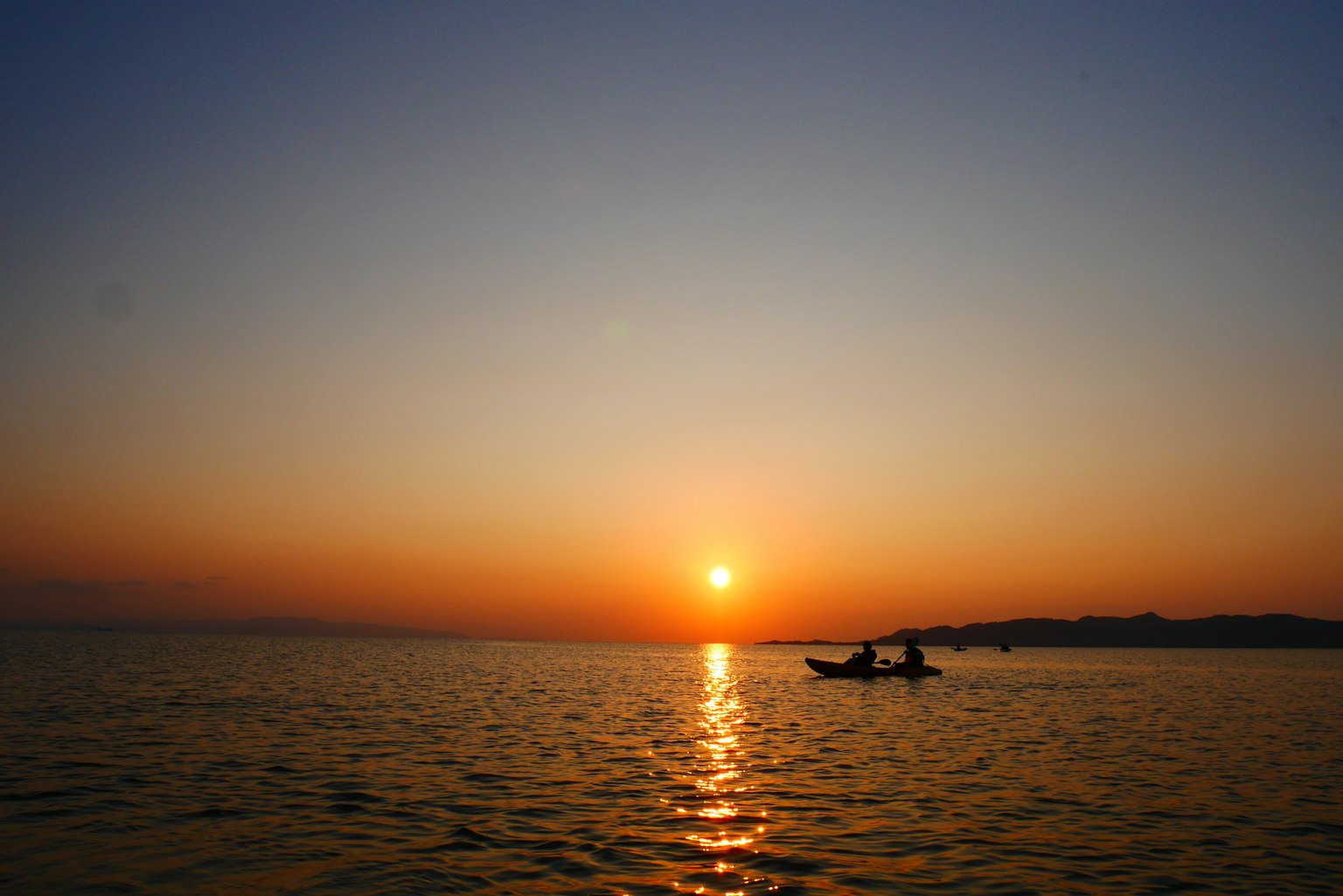 Deux pêcheurs dans un bateau avec un beau coucher de soleil sur l'eau