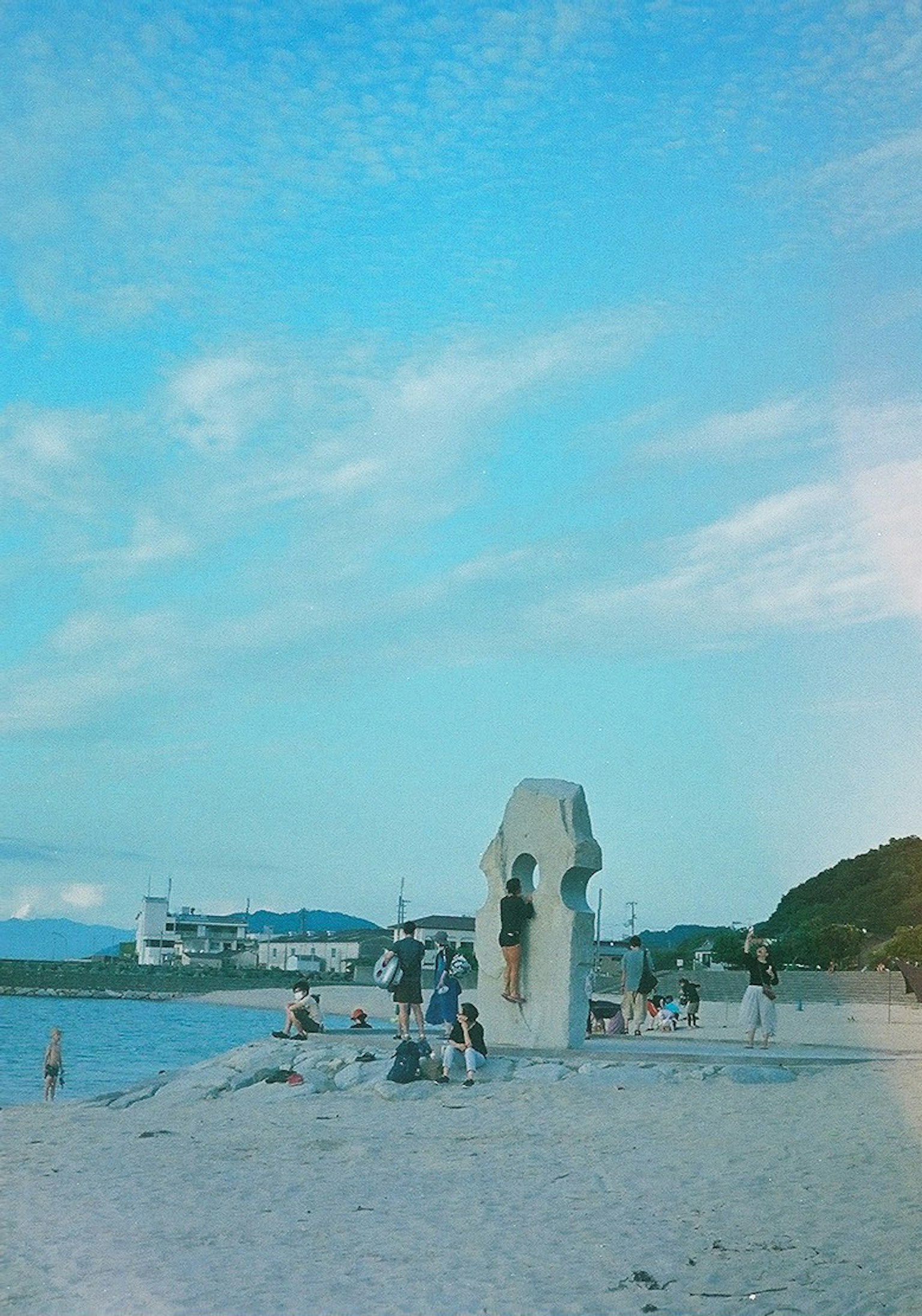 海滩场景，蓝天下有雕塑和人们