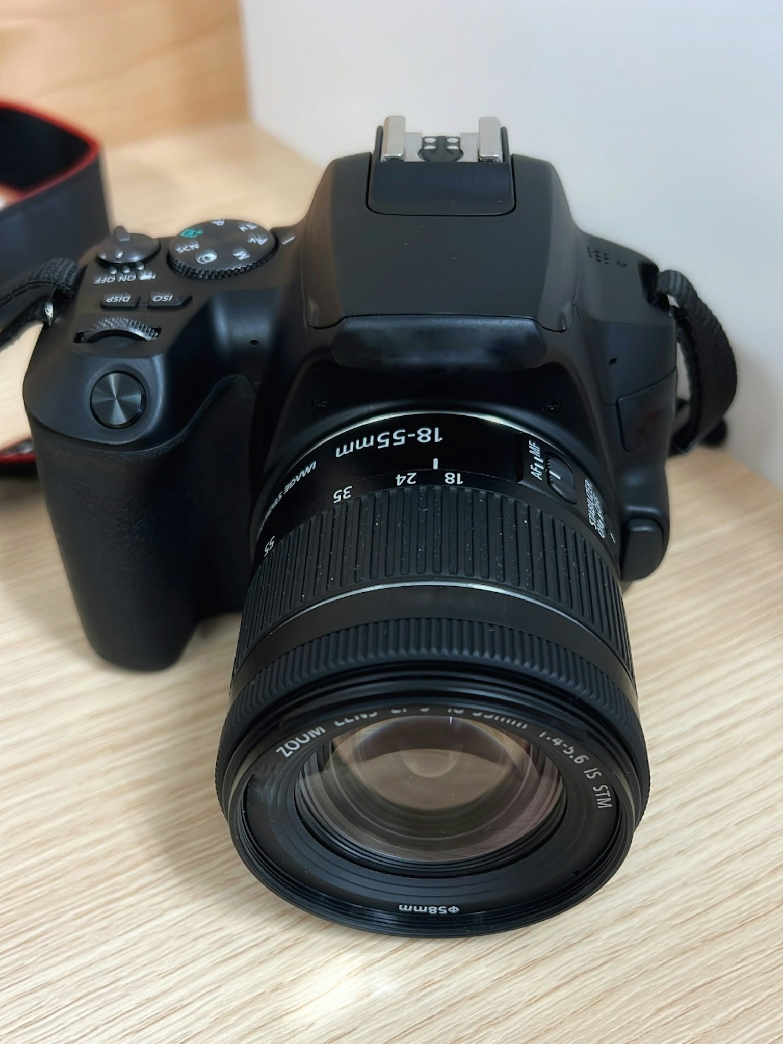 Cámara réflex digital negra colocada sobre una mesa de madera