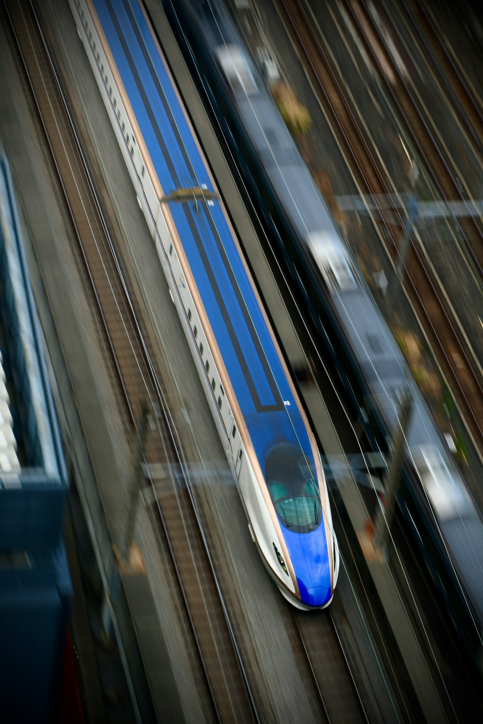 Un train Shinkansen bleu se déplaçant sur des rails vu du ciel