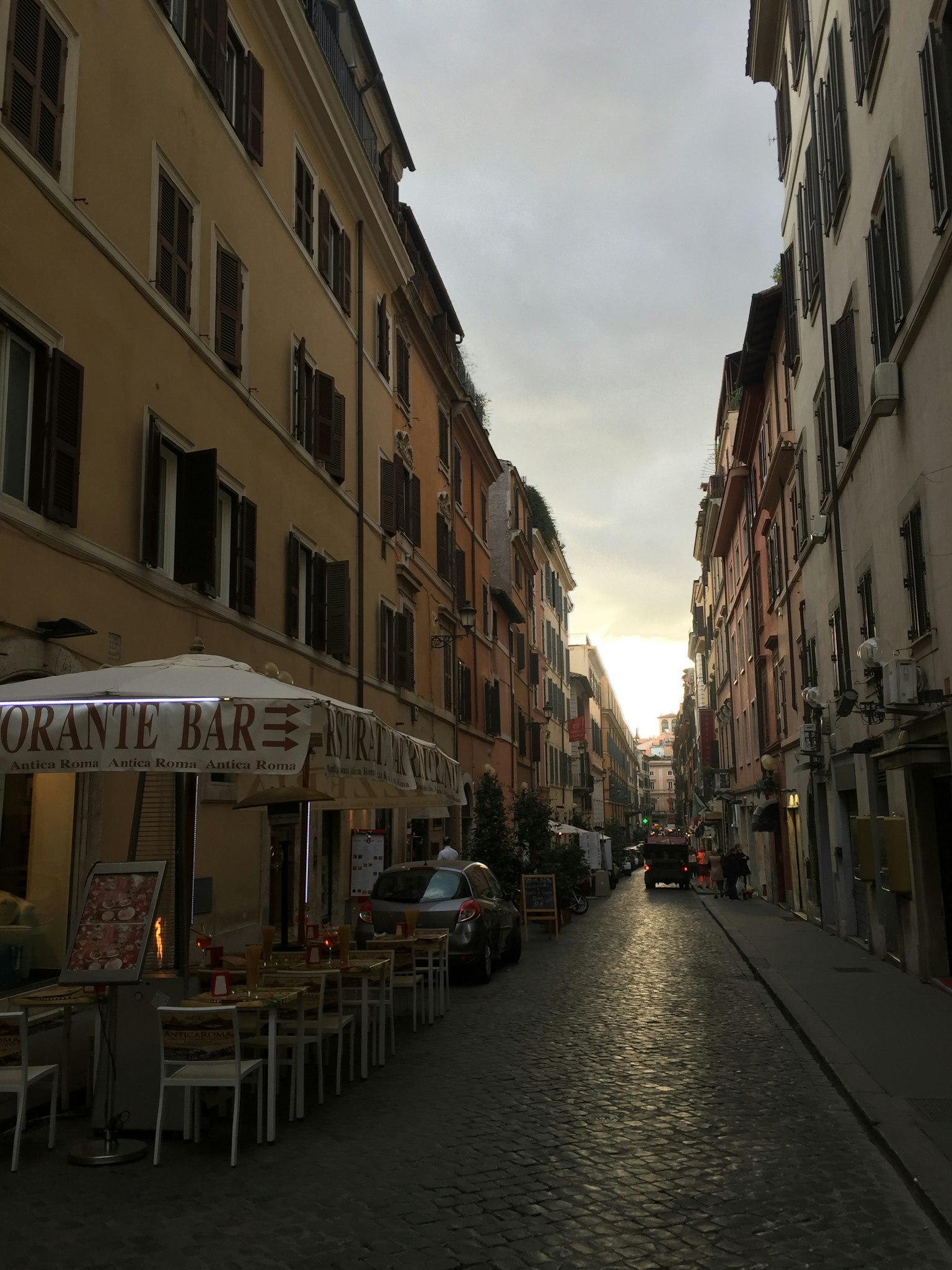 Quiet street scene in Rome featuring cafes and restaurants along a cobblestone path