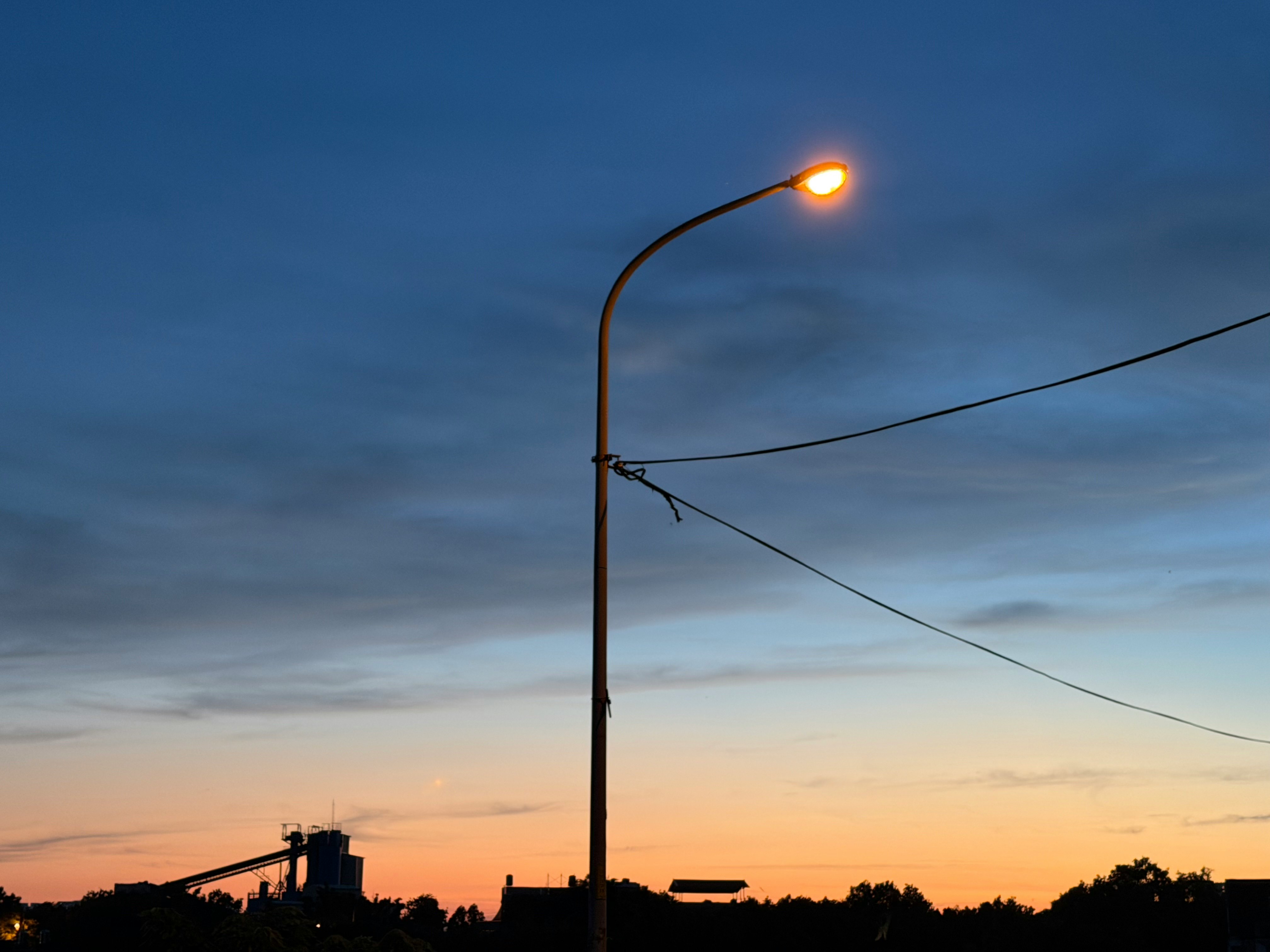夕暮れの空に伸びる街灯と電線のある風景
