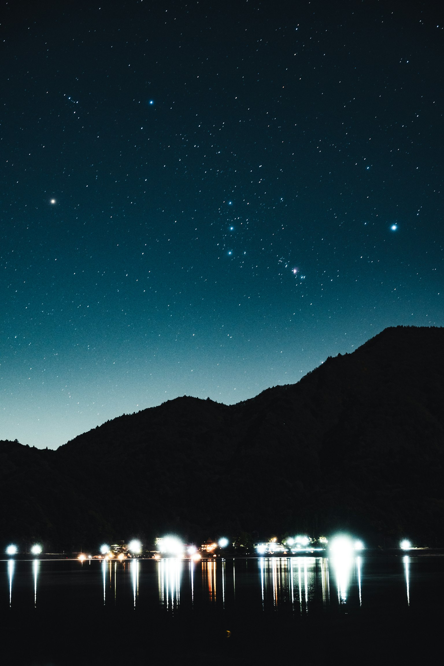 星空と山々が映る静かな湖の夜景