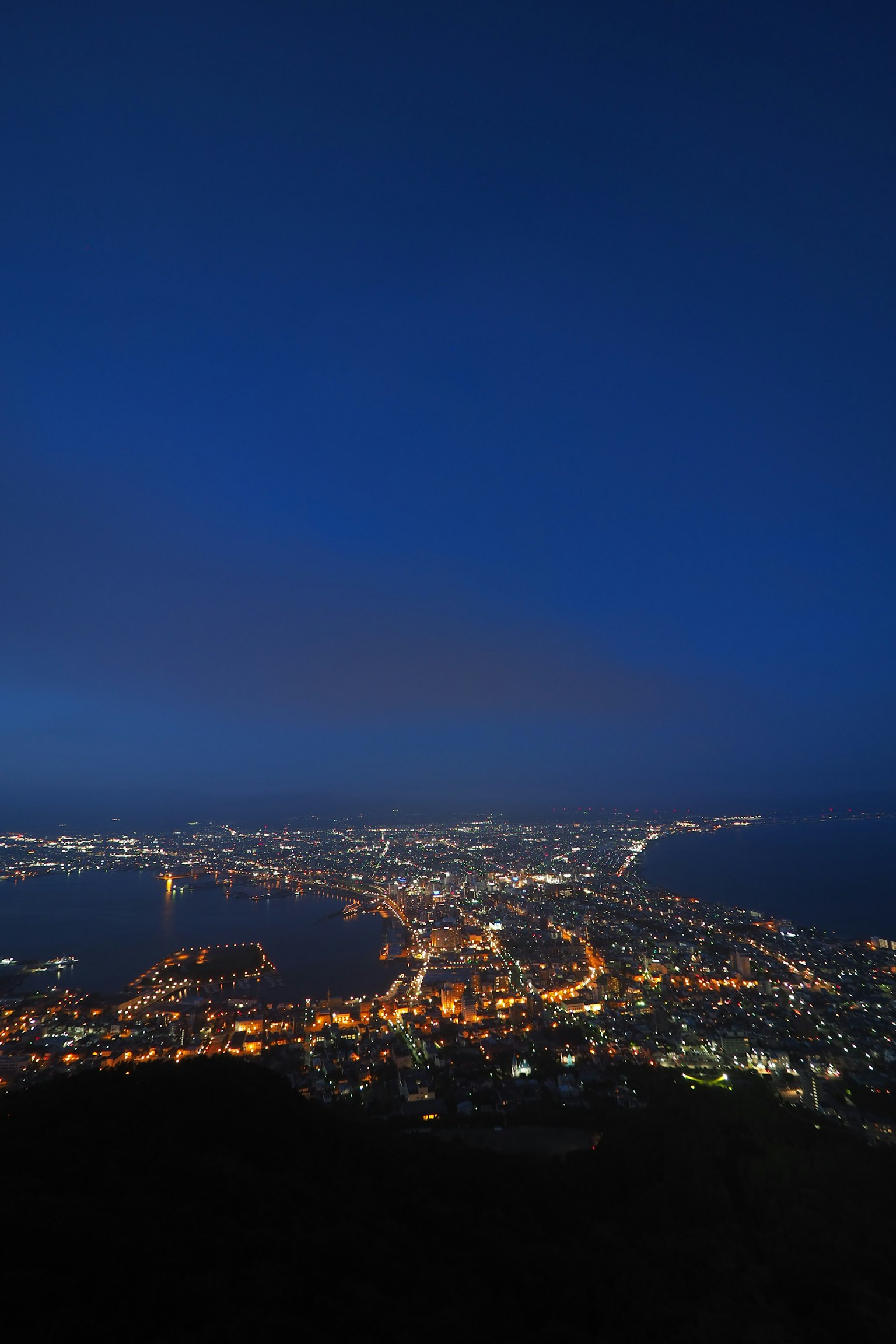 Vista nocturna de un horizonte urbano con edificios iluminados y costa