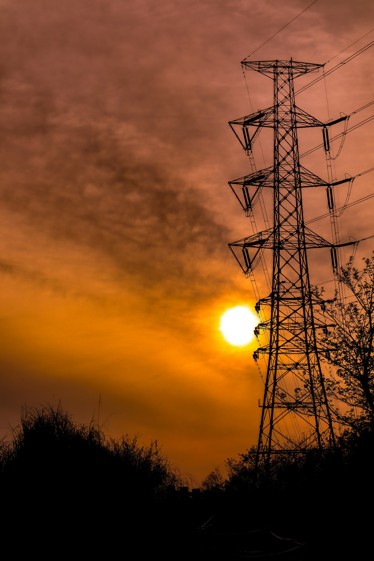Silueta de una torre eléctrica contra un cielo al atardecer