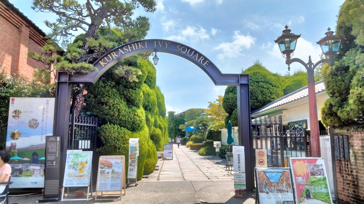 Entrada en arco a un jardín exuberante con farolas decorativas