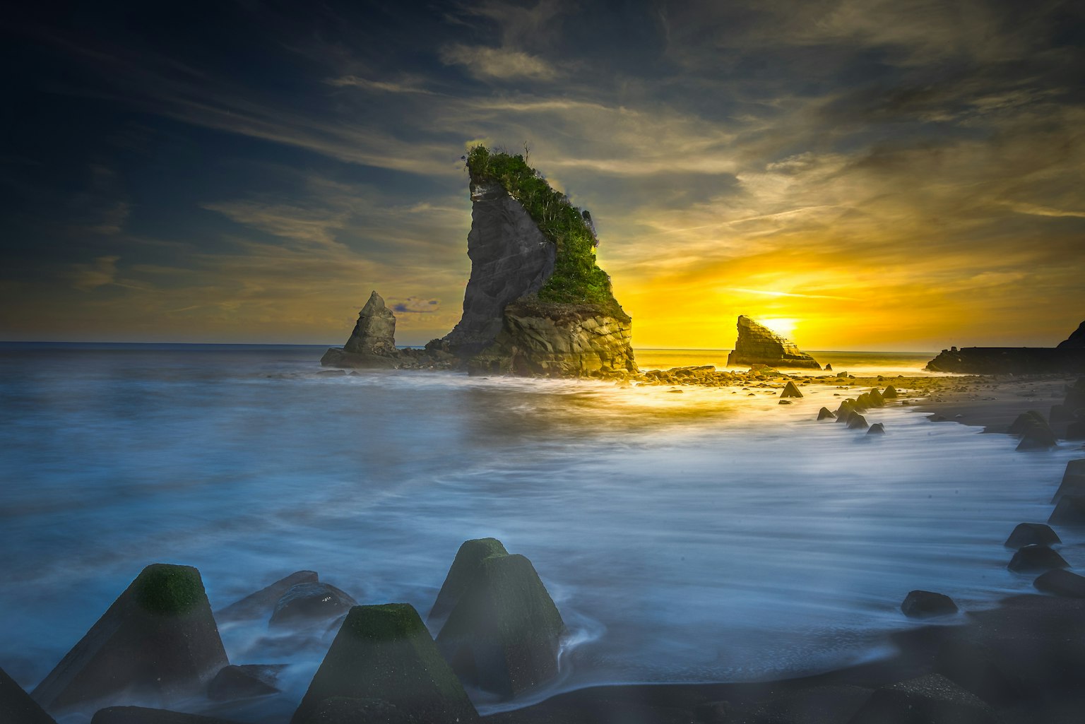 Vue panoramique d'une formation rocheuse verte au coucher du soleil sur l'océan