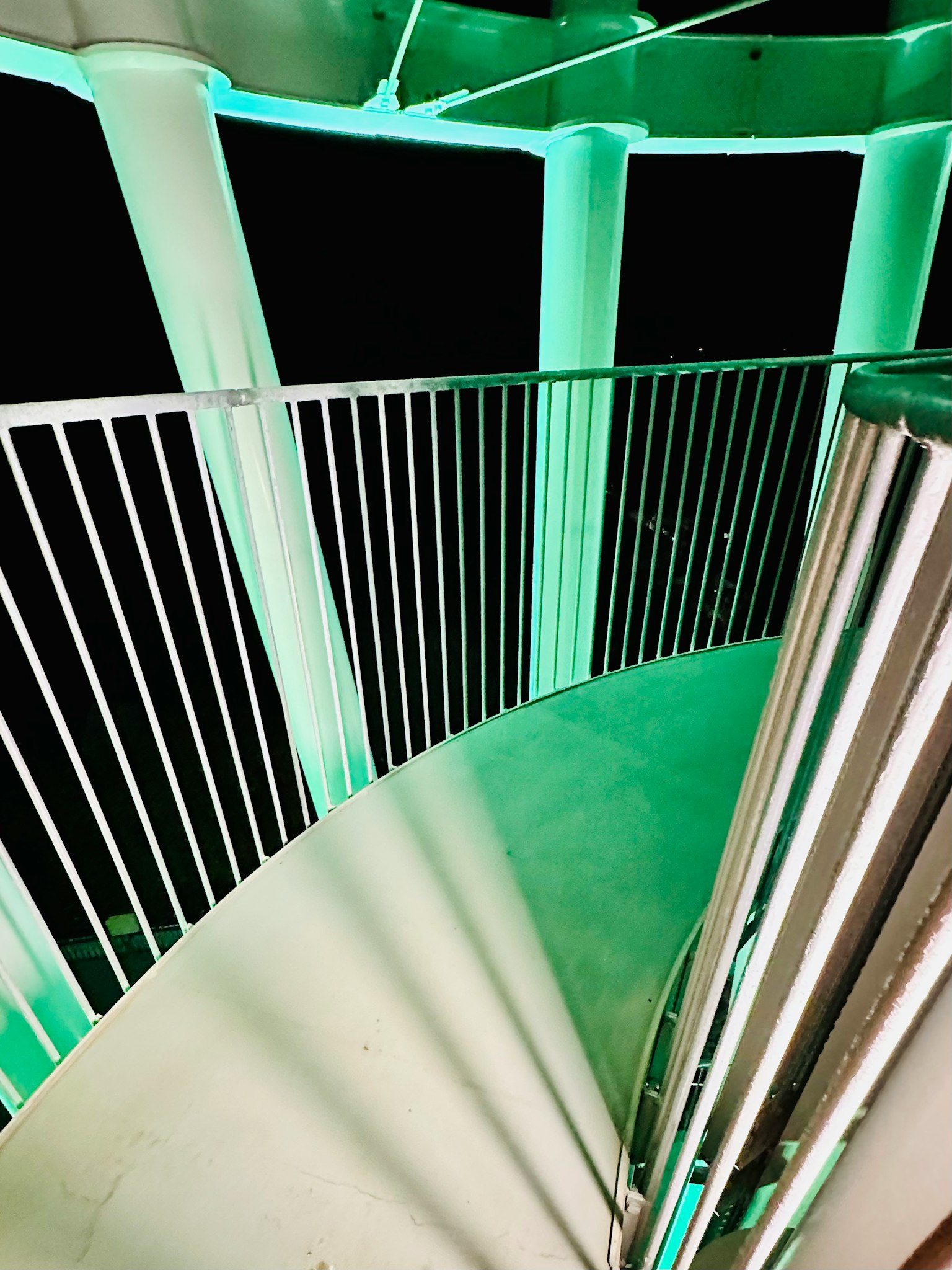 Vista desde arriba de una escalera en espiral iluminada con luz verde