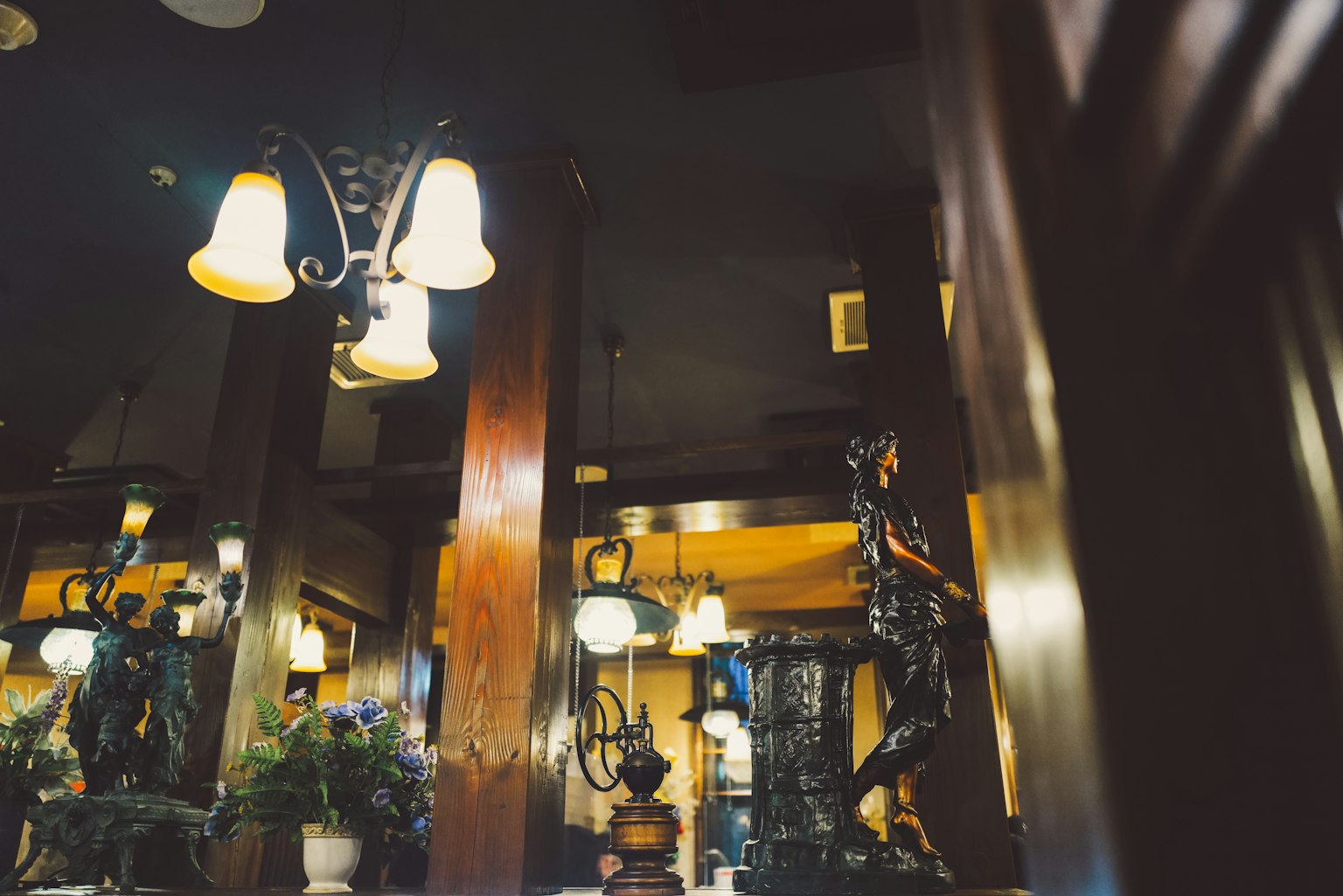 Innenansicht eines schwach beleuchteten Restaurants mit Lampen und Skulpturen