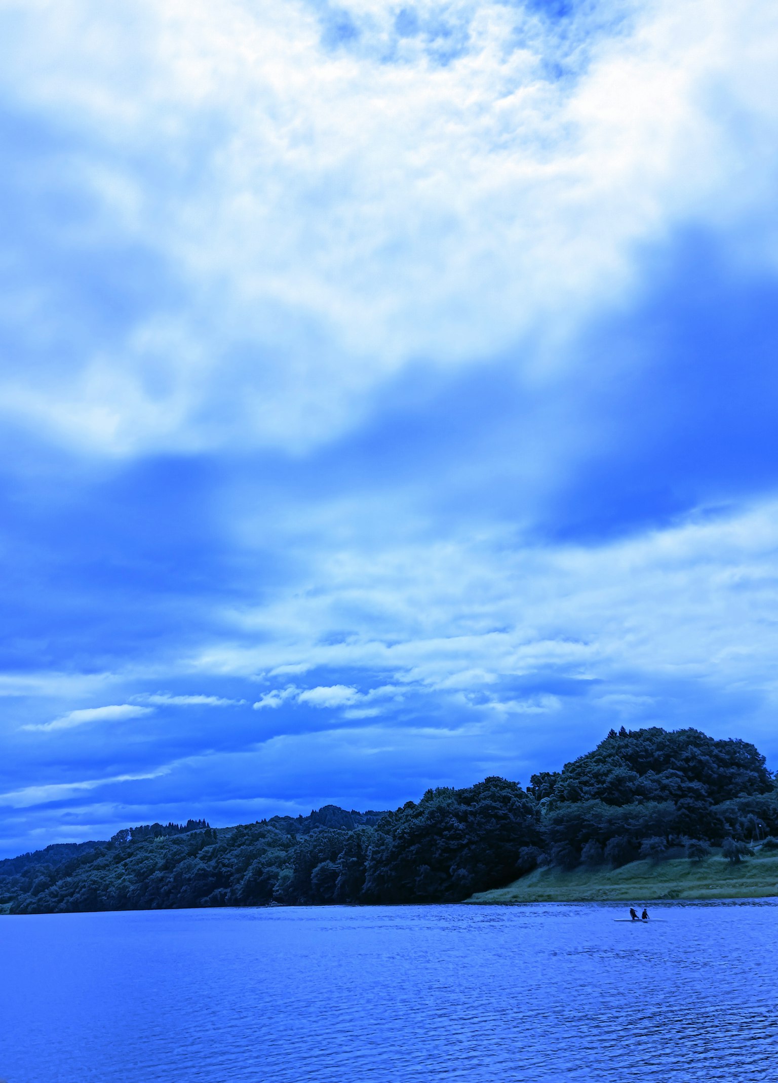 Blue lake with a cloudy sky and lush greenery