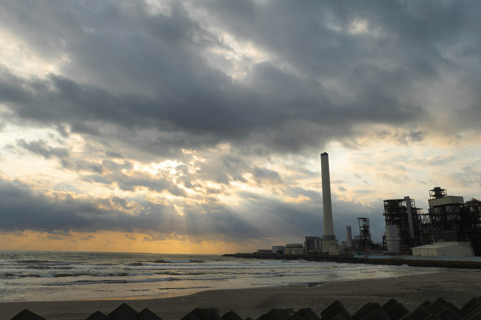 海灘和工廠煙囪的日落景觀
