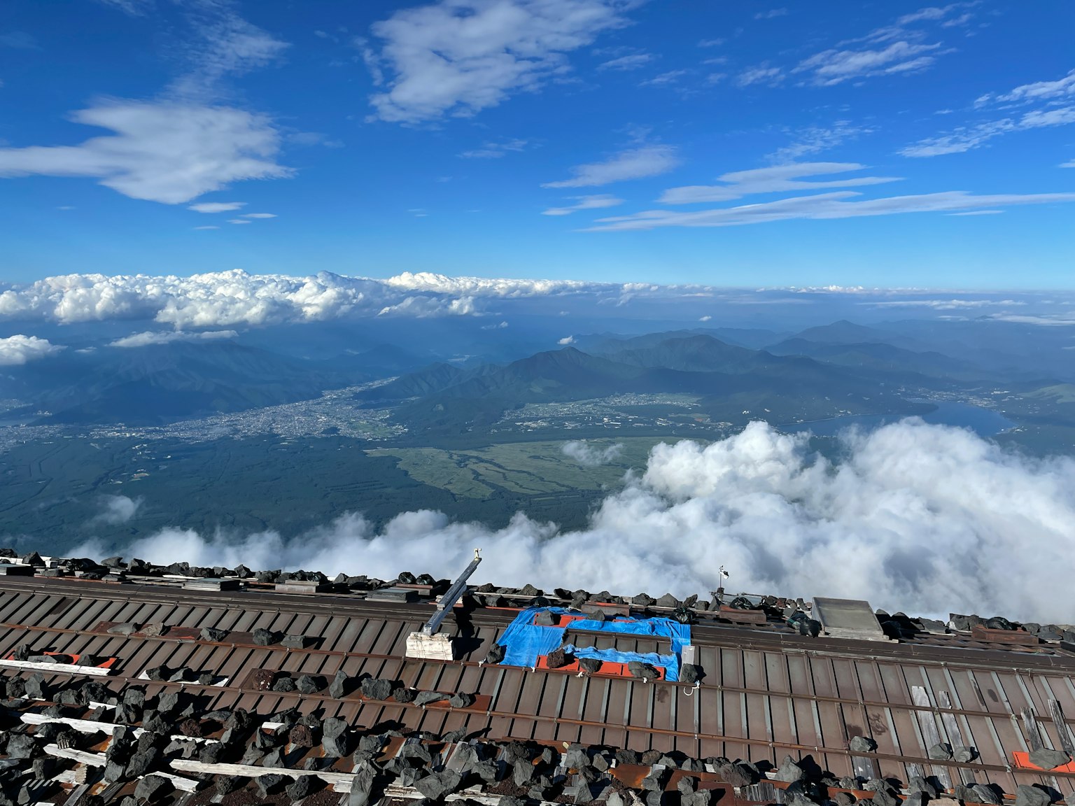 Vue panoramique depuis un sommet de montagne avec ciel bleu et nuages
