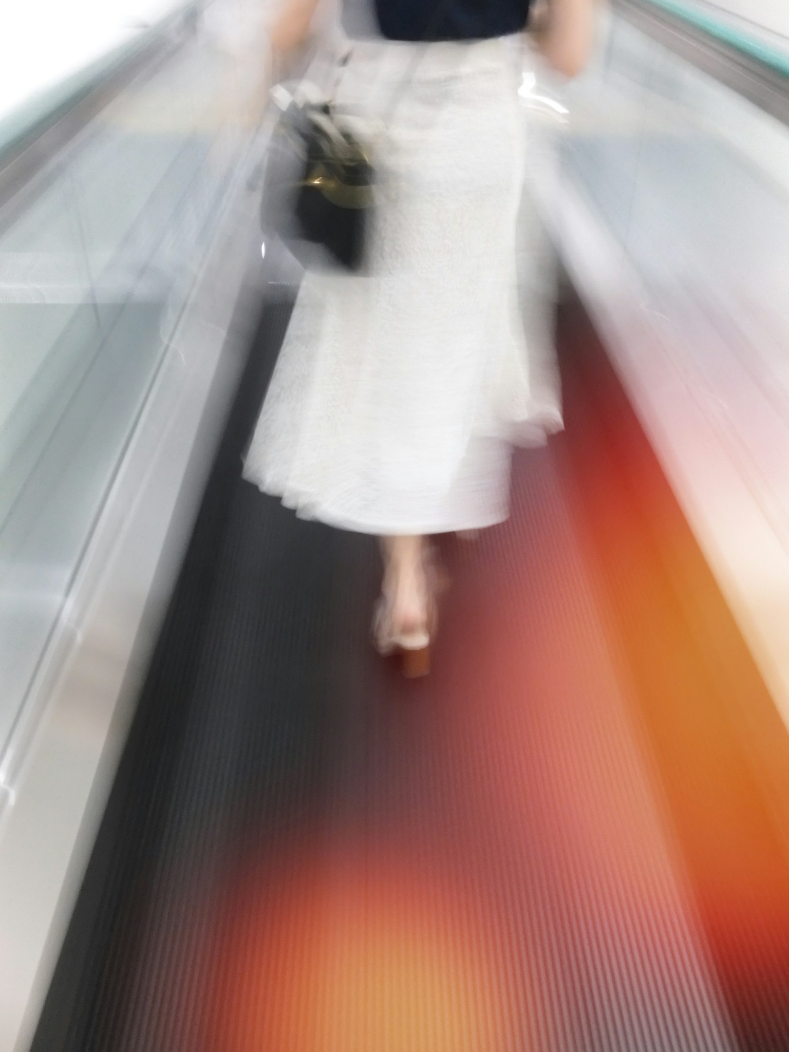 Seorang wanita berjalan di eskalator dengan efek kabur