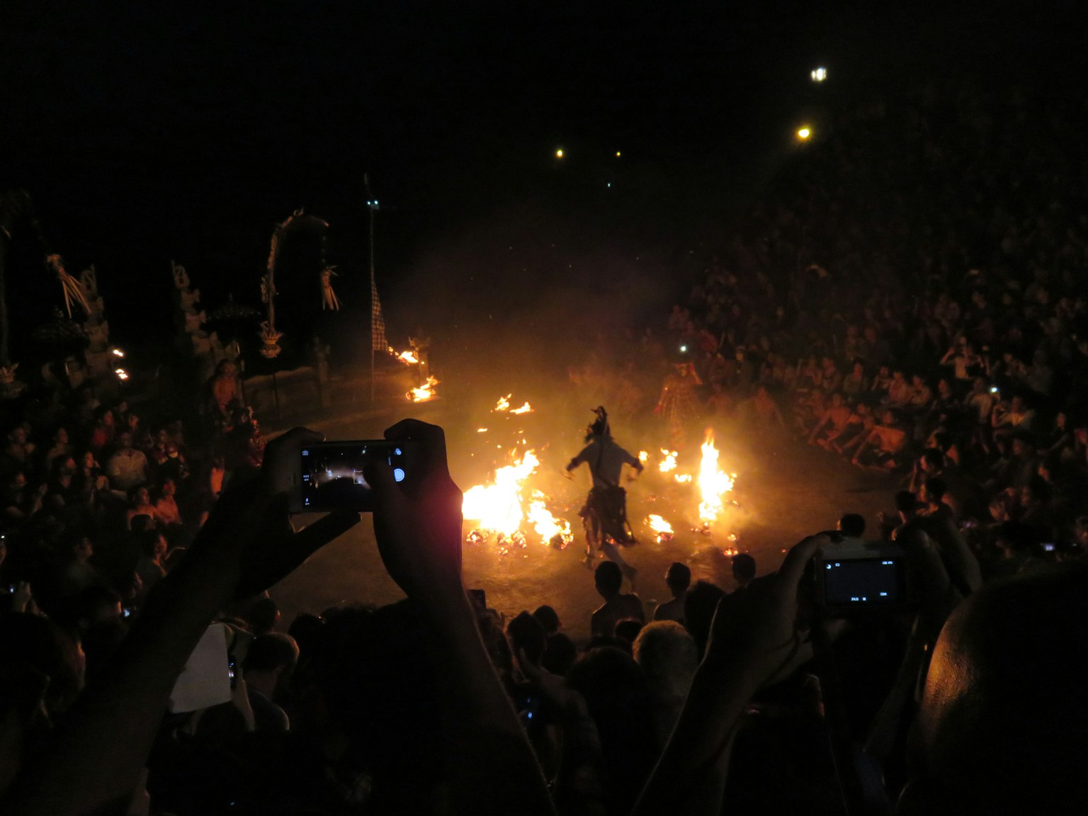 Un artista che usa il fuoco di fronte a un pubblico con spettatori che scattano foto