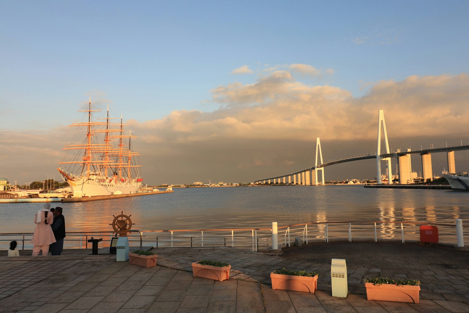 Vue pittoresque d'un voilier au coucher de soleil près d'un pont