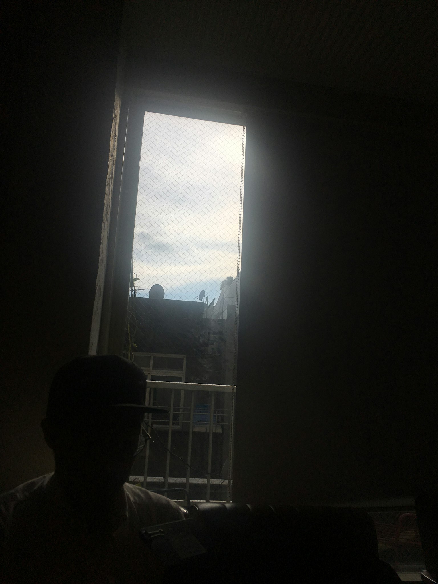 Kamar redup dengan jendela yang menunjukkan langit mendung