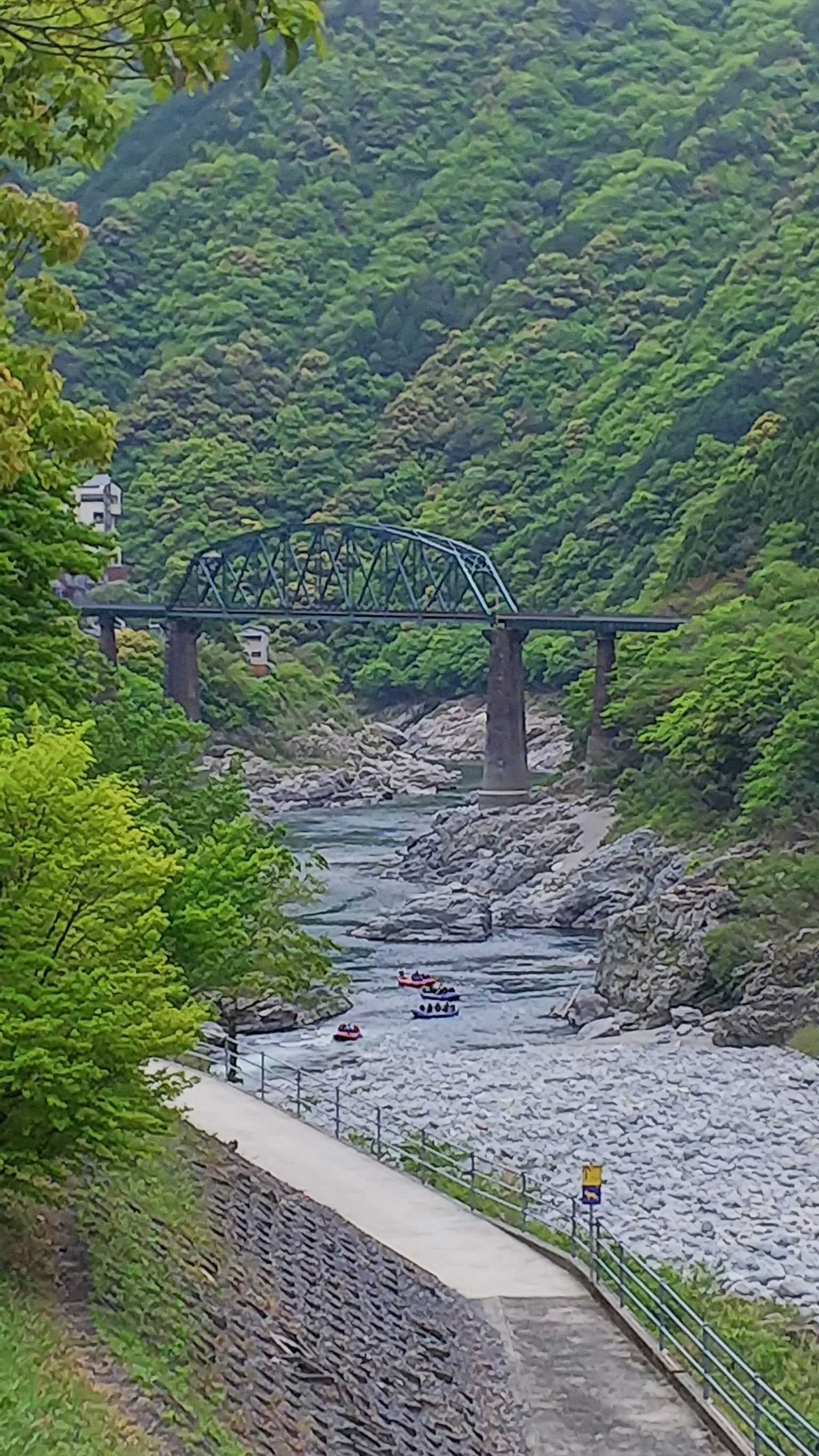 Eine blaue Eisenbahnbrücke über einen Fluss, umgeben von üppigen grünen Bergen