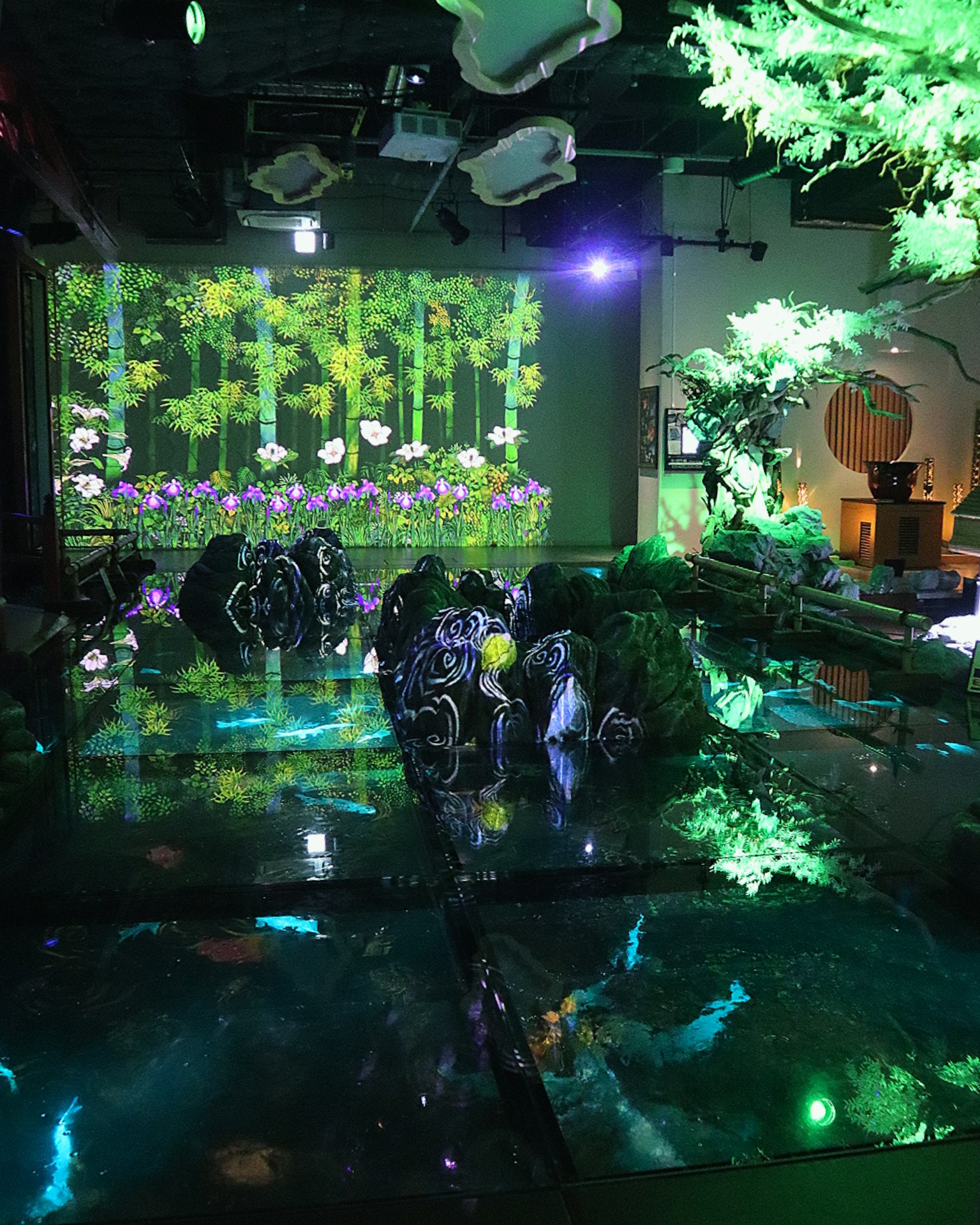 Un espacio de exhibición interactivo que presenta una escena de bosque verde fantástica con proyecciones visuales