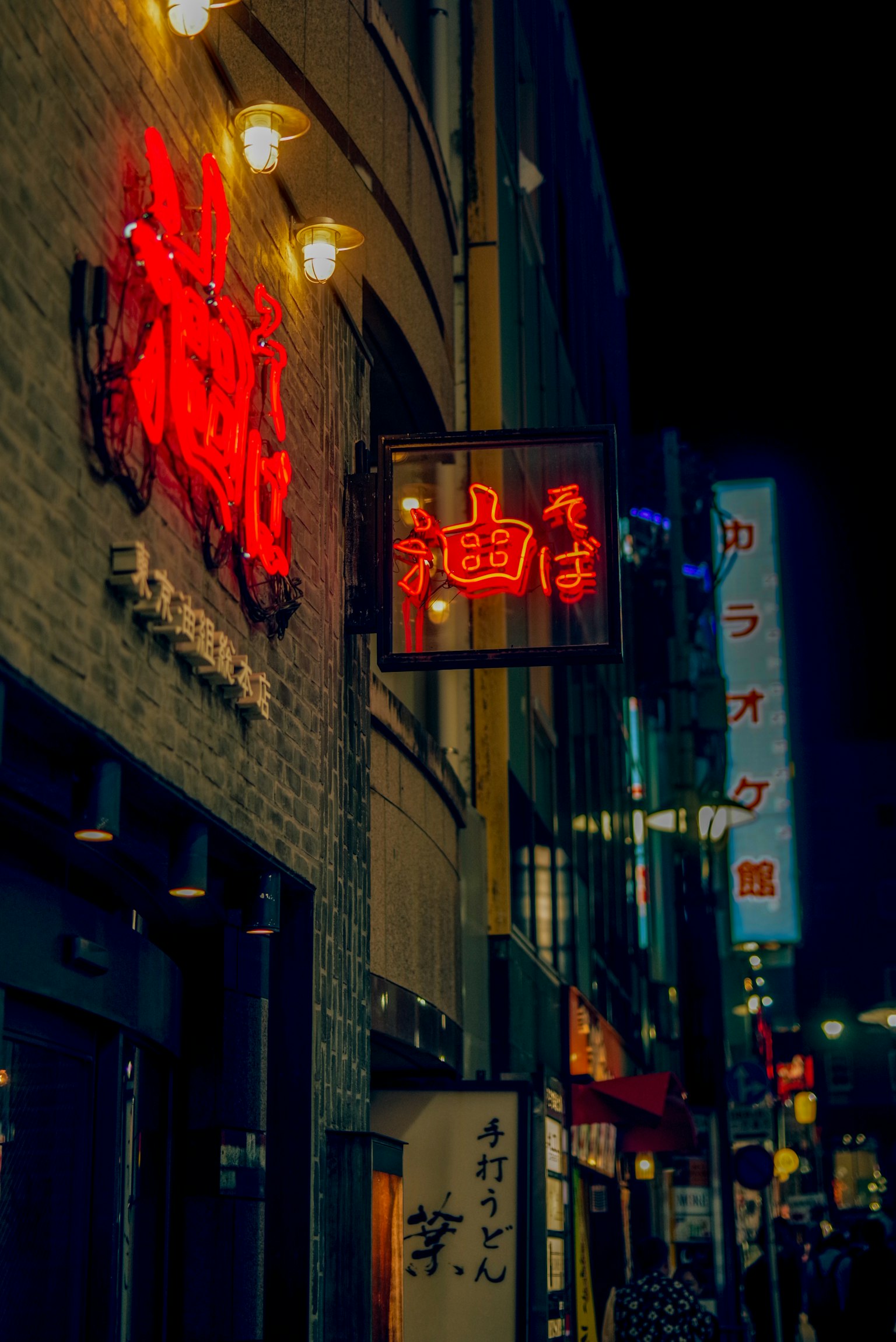 Night street scene featuring red neon signs and restaurant facades
