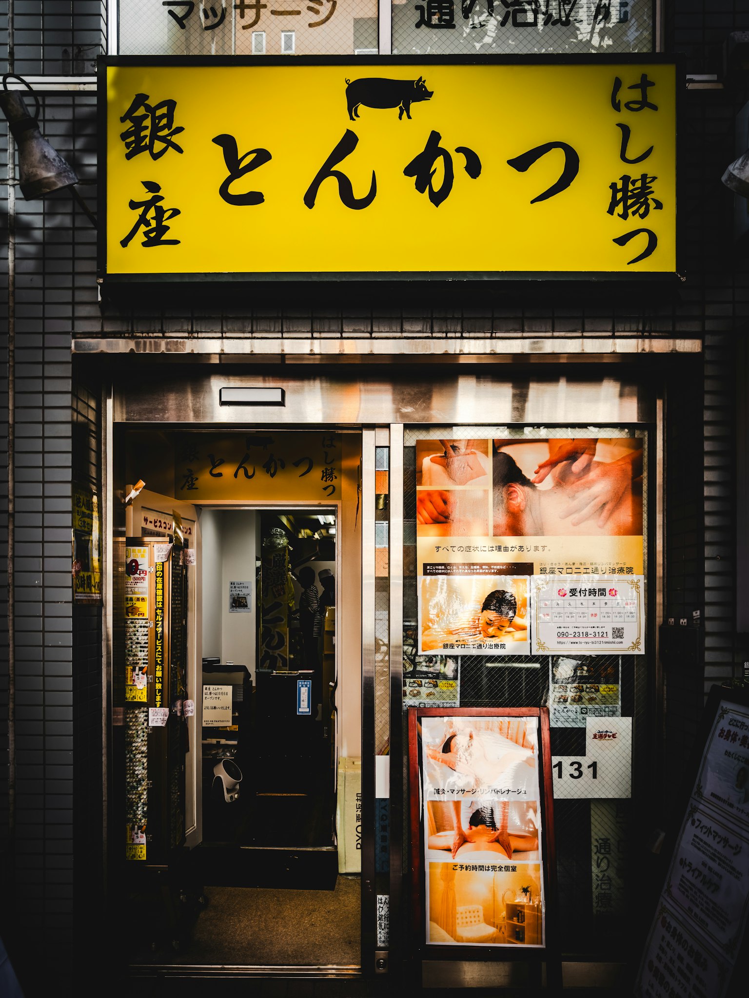 Pintu restoran tonkatsu di Ginza dengan papan nama kuning cerah dan menu yang terlihat