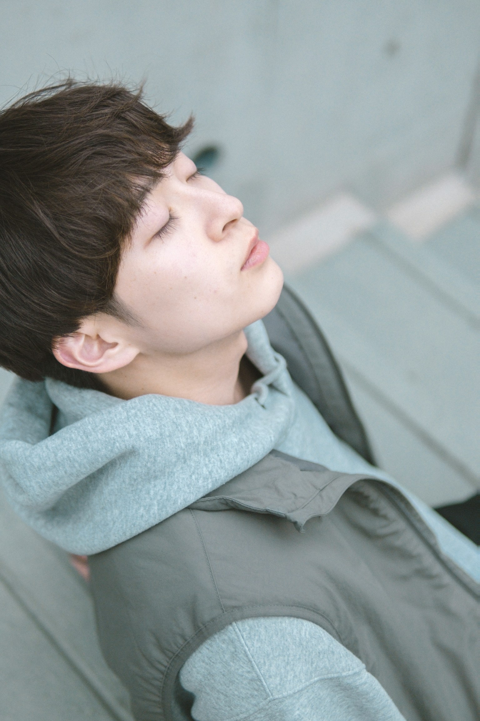 A young man wearing a gray hoodie is looking up