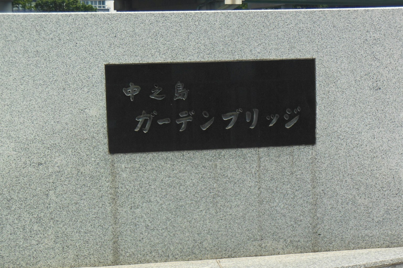 Black sign for Nakashima Garden Bridge set against a stone background