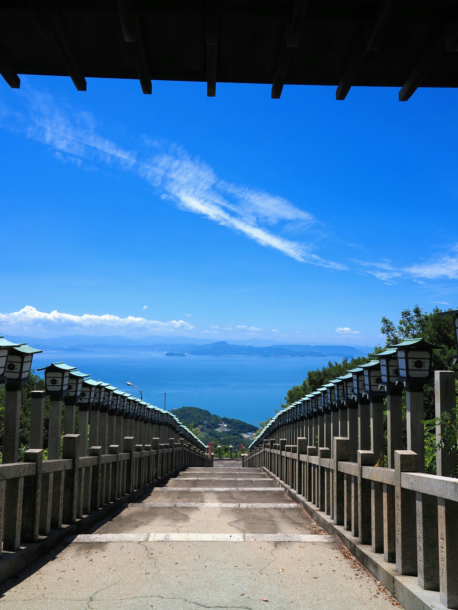 Escalera que baja hacia el océano bajo un cielo azul