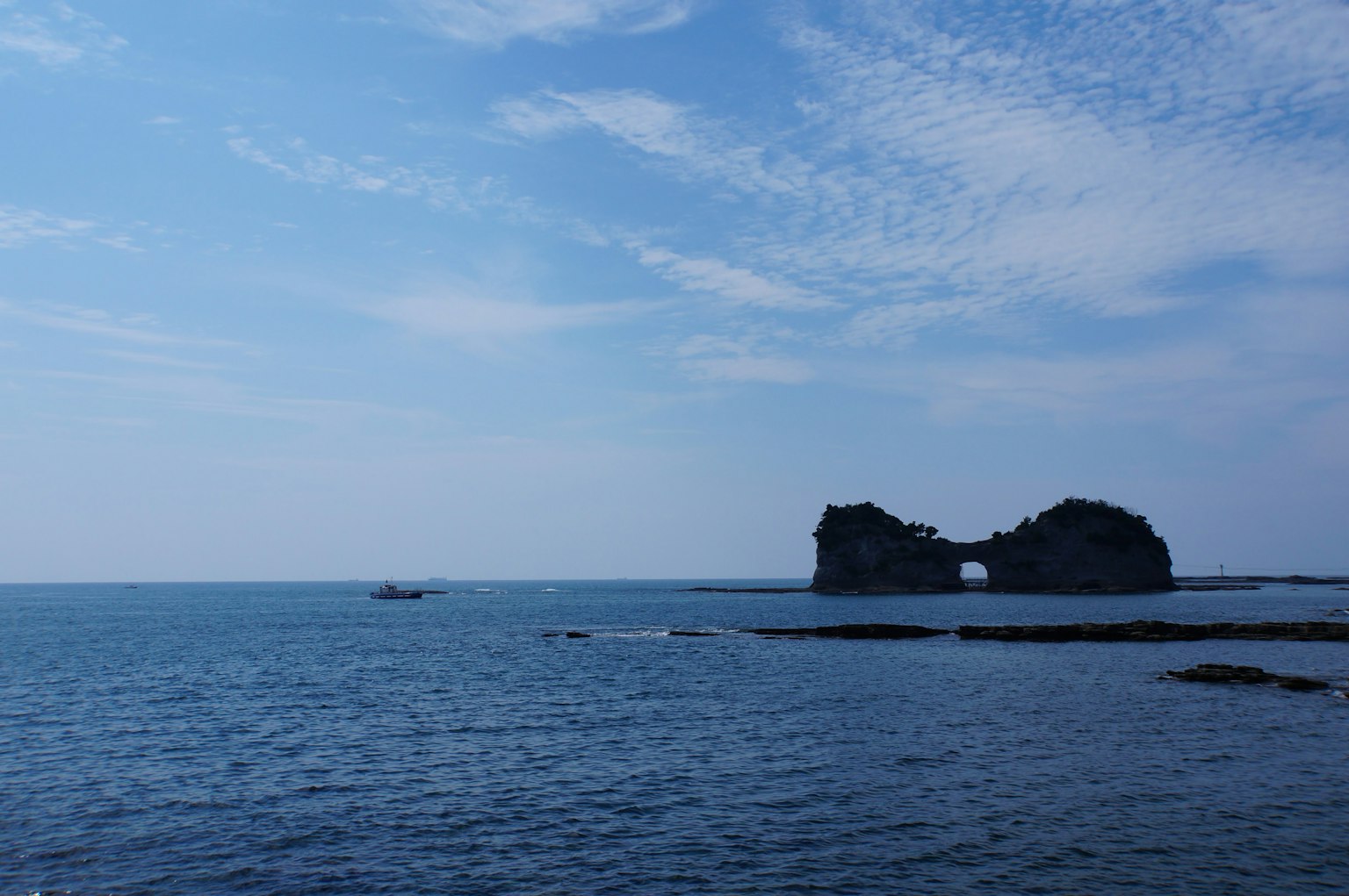 เงาของเกาะหินในท้องฟ้าสีฟ้าและทะเลที่สงบ