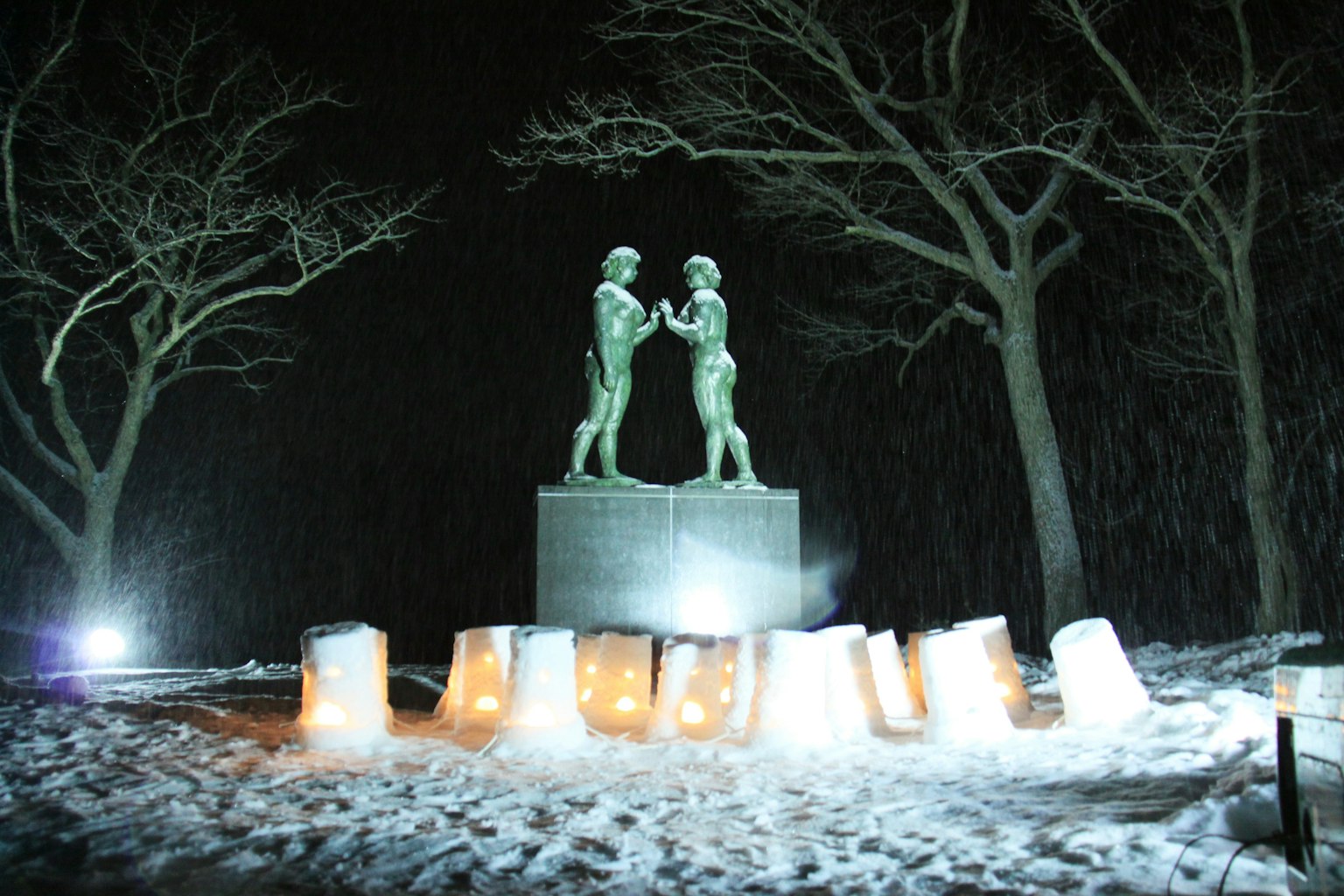 Estatua de dos figuras de pie en la nieve con bloques de hielo brillantes alrededor