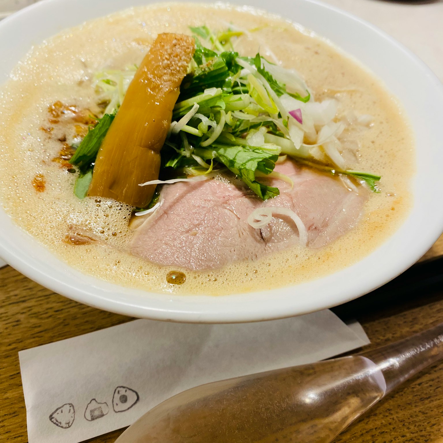 一碗拉麵，上面放著豬肉片和各種蔬菜