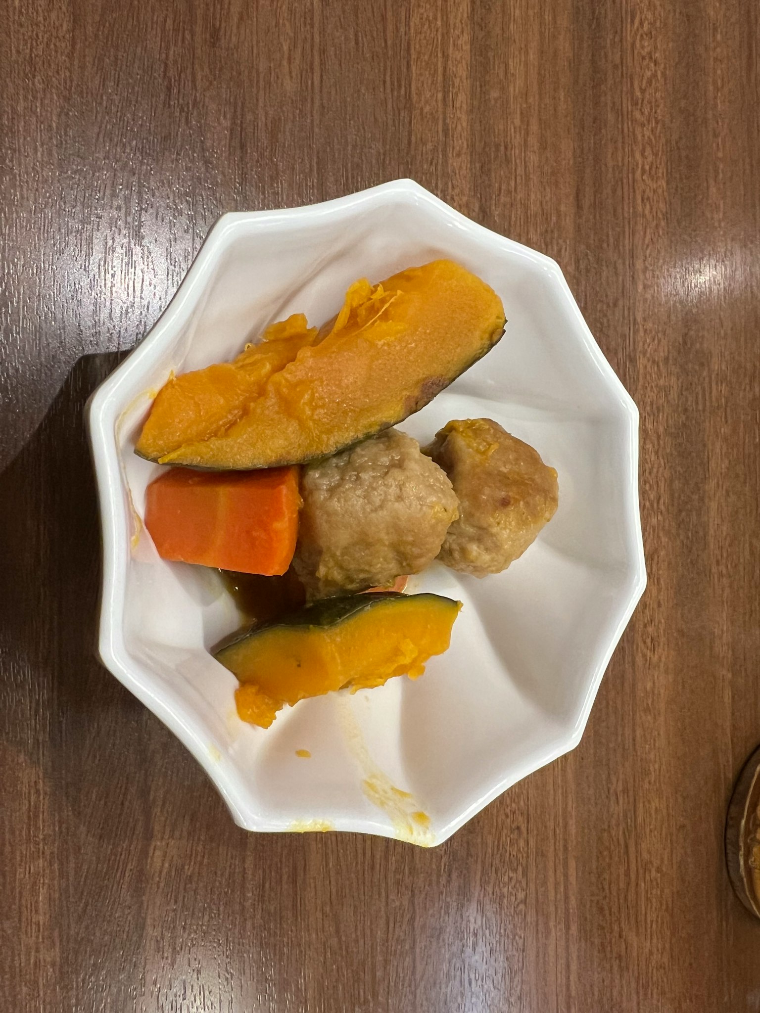 一個白色盤子裡有南瓜、胡蘿蔔和肉丸