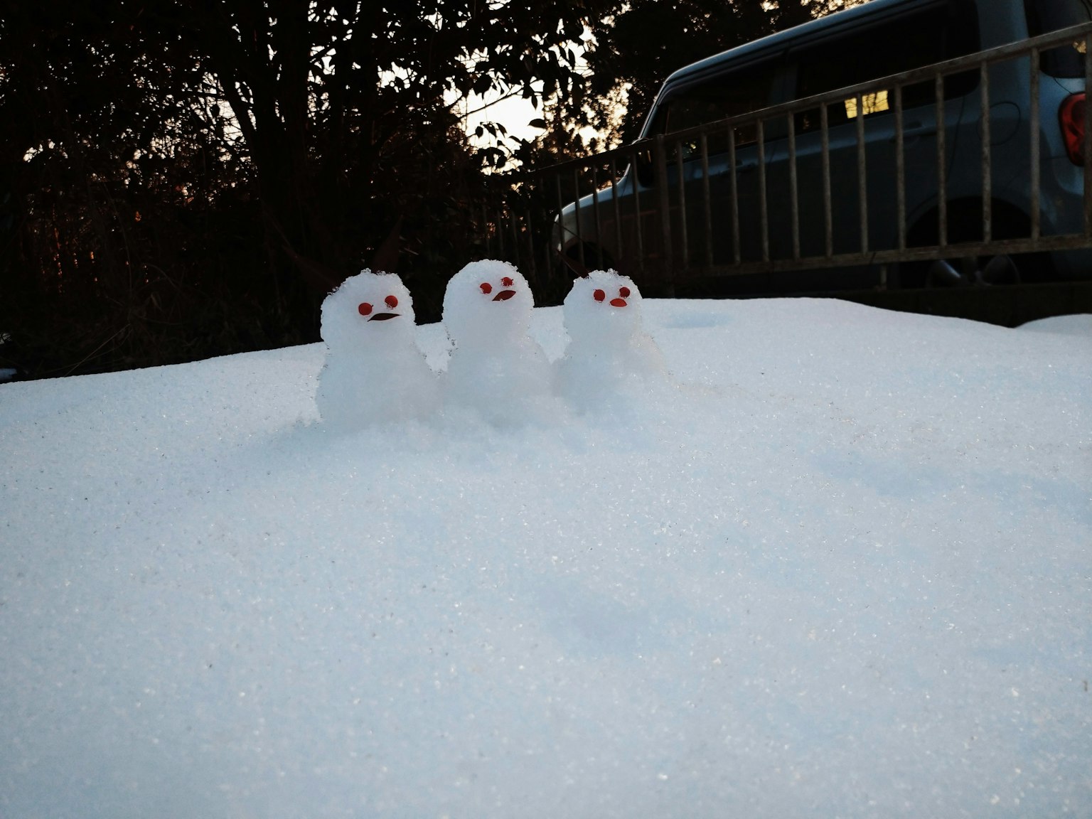 三只小雪人，红色的眼睛和嘴巴，站在雪地上