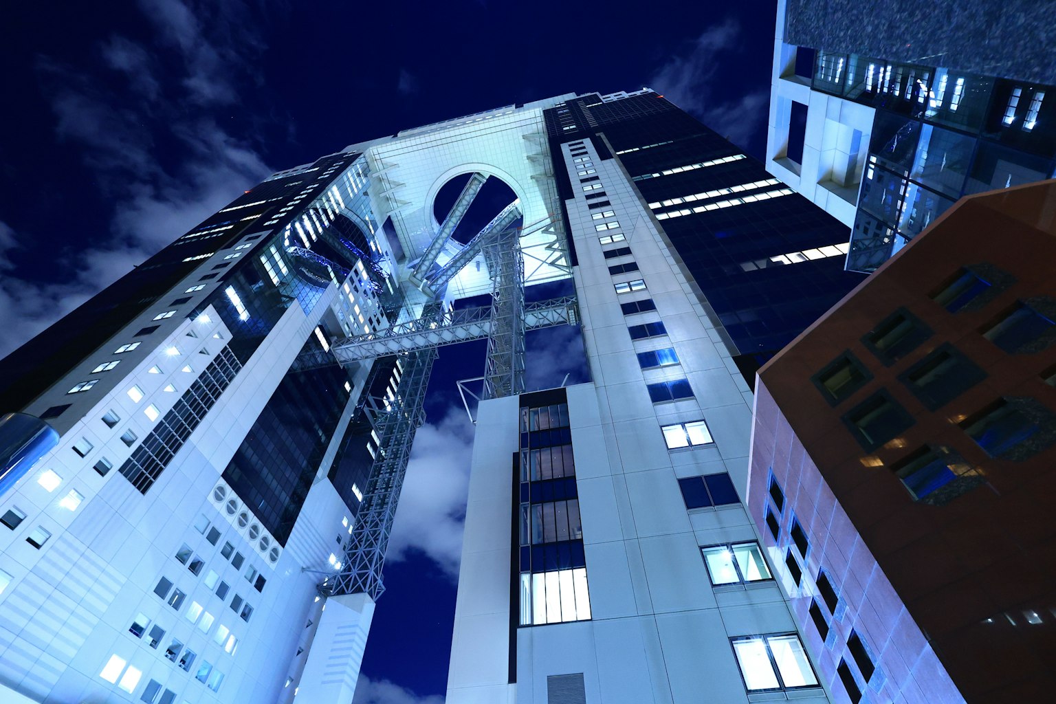 Paisaje urbano nocturno con rascacielos vista desde abajo tonos azules y blancos brillantes