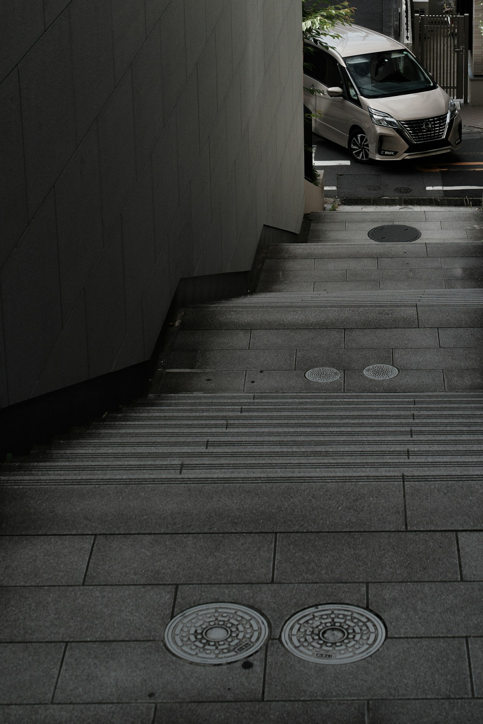 View from the top of stairs showing a car and urban scenery
