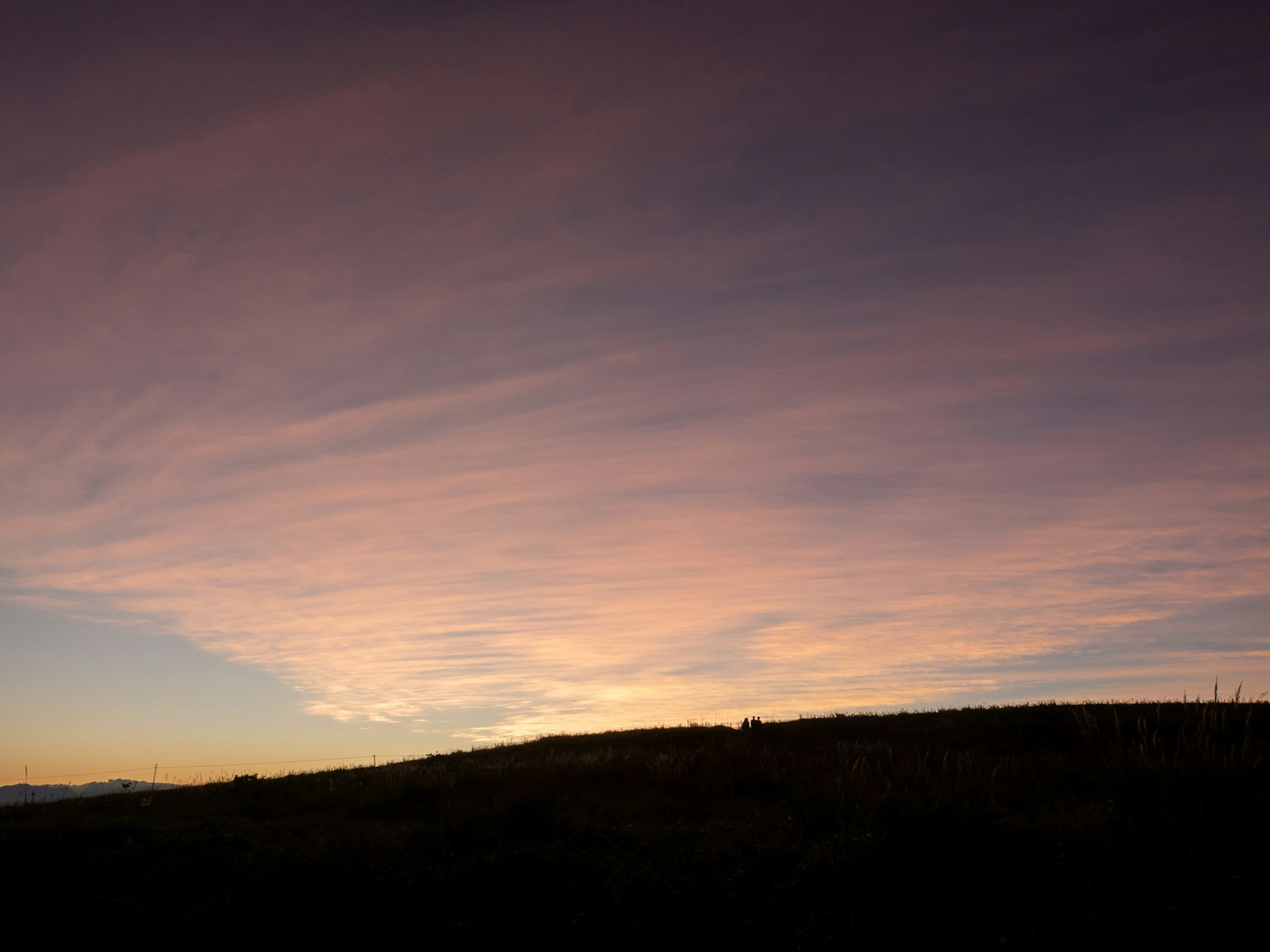 Malerischer Sonnenuntergangshimmel mit sanften Farbtönen über einer Silhouette von Hügeln