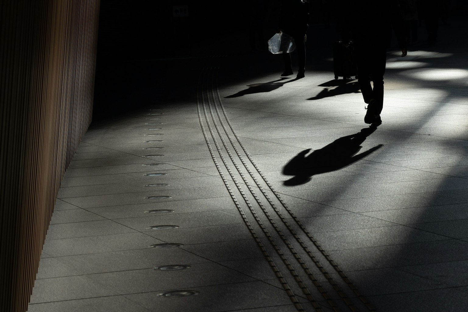 Siluetas de personas caminando en sombras con contraste de luz