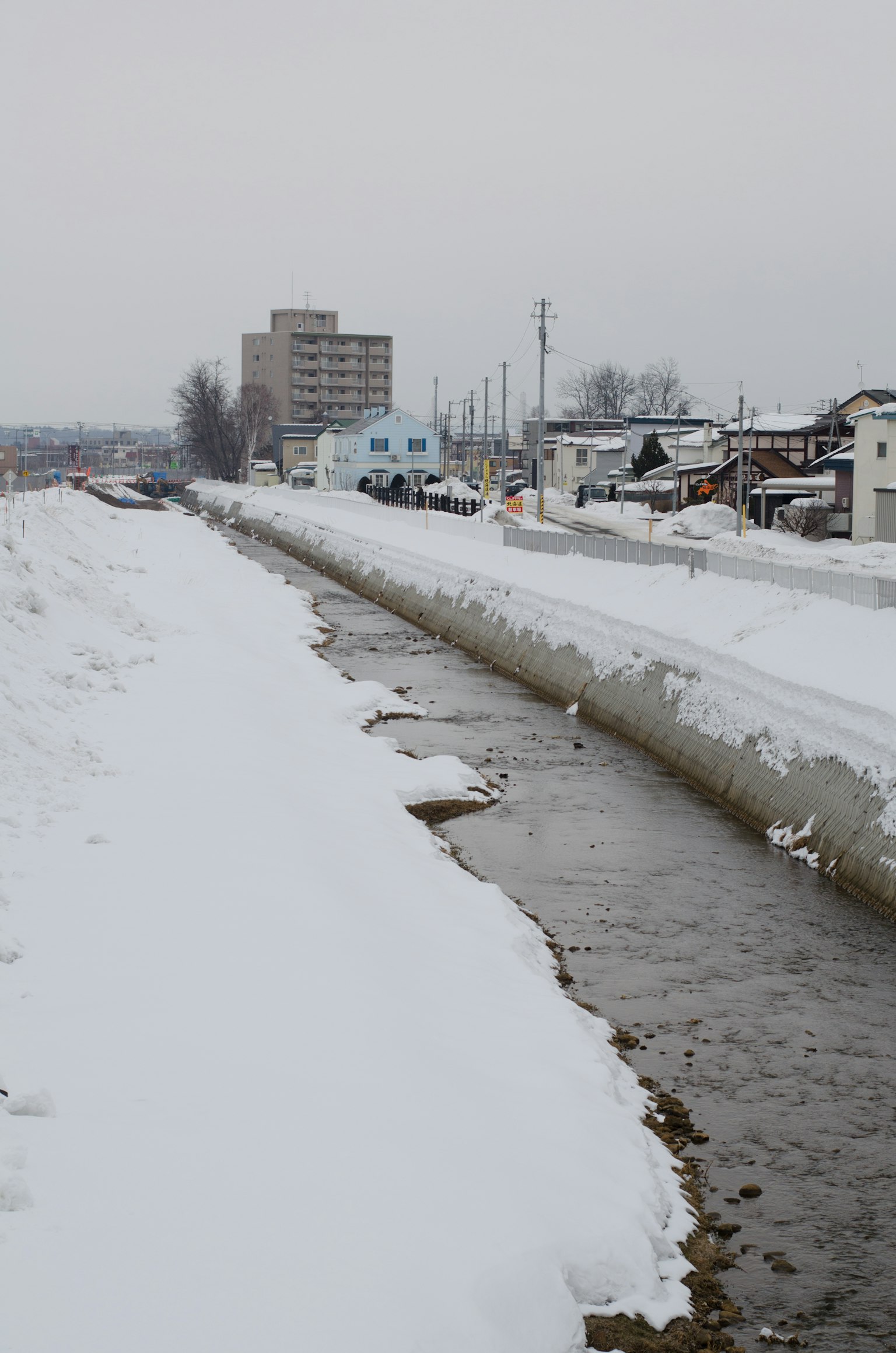 Schneebedeckter Fluss mit umliegenden Gebäuden