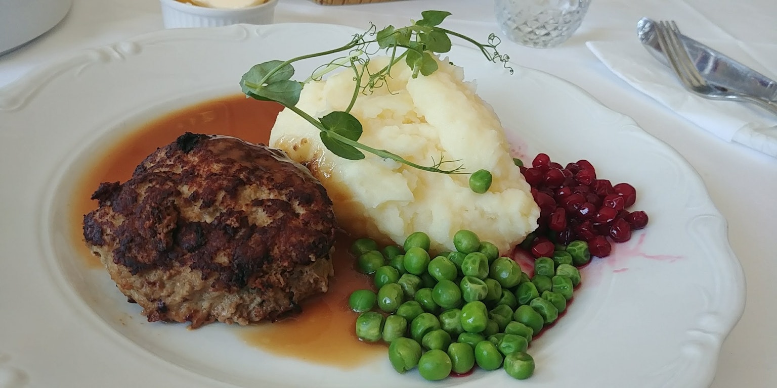 Một đĩa có bánh hamburger khoai tây nghiền đậu xanh và hạt lựu