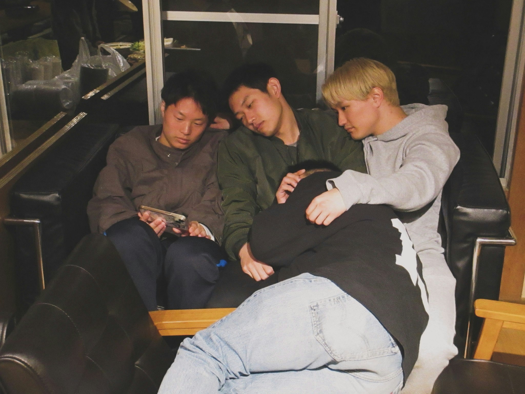 ソファに並んでスマホを見つめる3人の友人