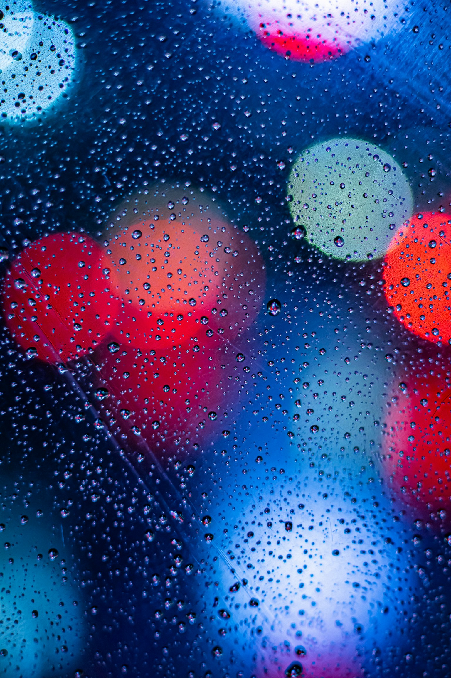 Lumières colorées floues vues à travers une fenêtre mouillée