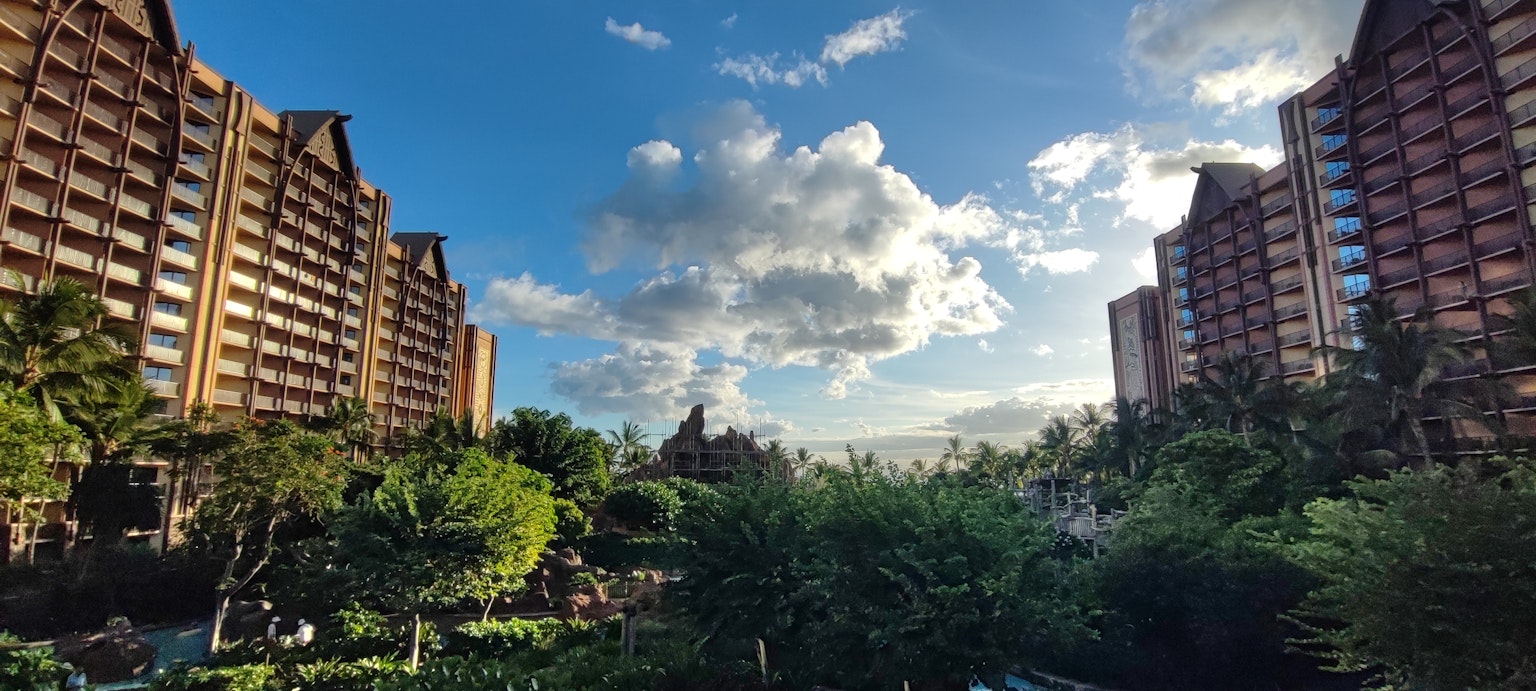 Grands immeubles flanquant un jardin luxuriant sous un ciel bleu avec des nuages