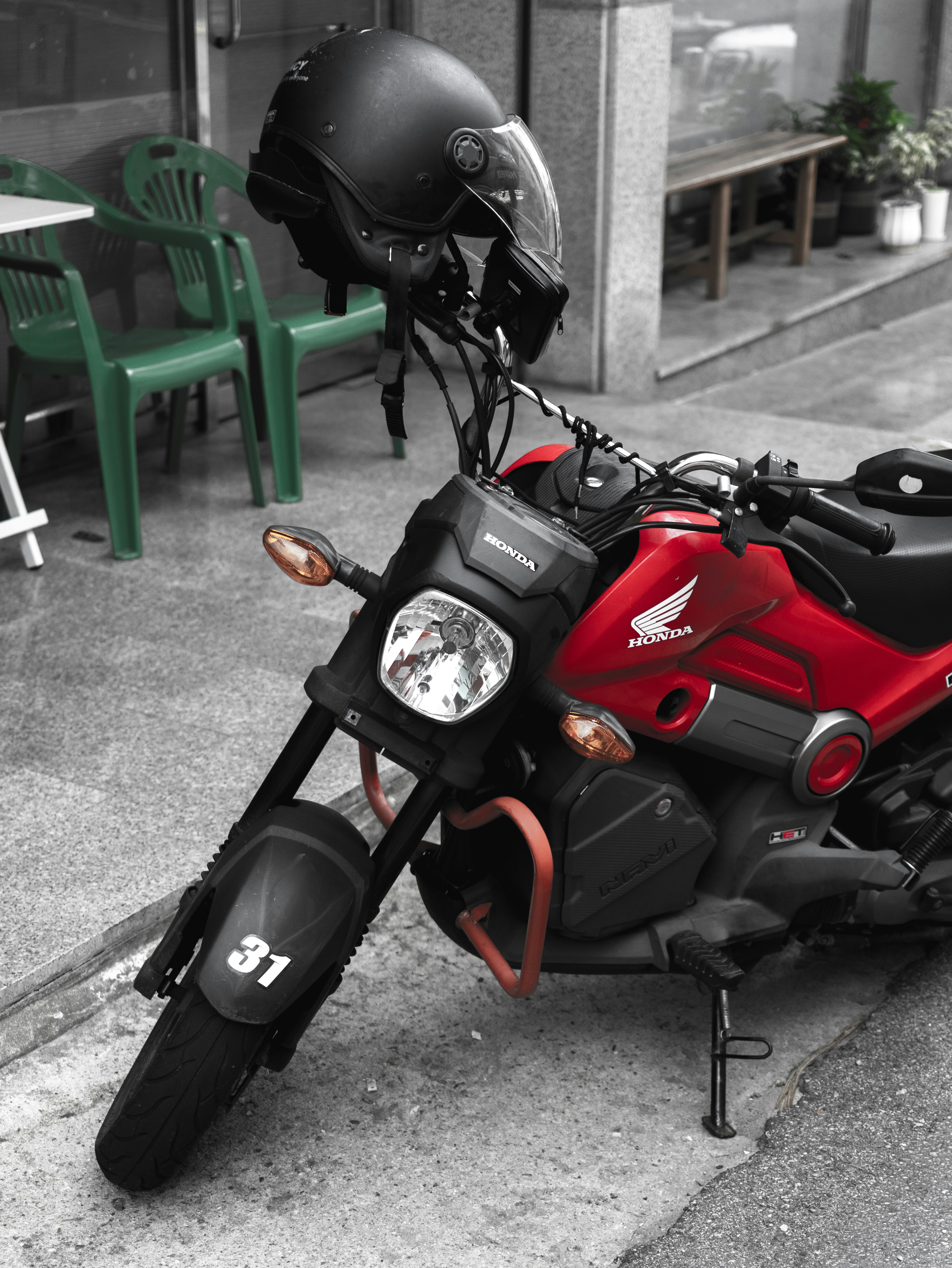 路地の壁際に停められた赤いバイクとヘルメットのある駐輪スペース