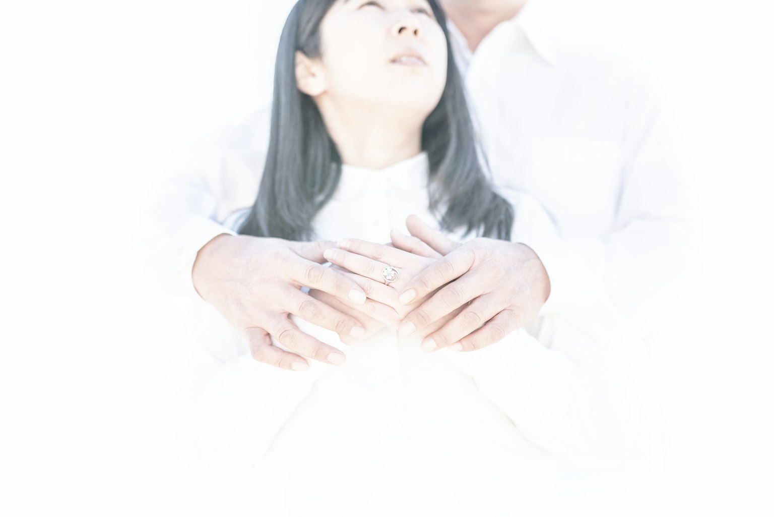 一名穿著白色衣服的男人在柔和而空靈的環境中擁抱一名女性