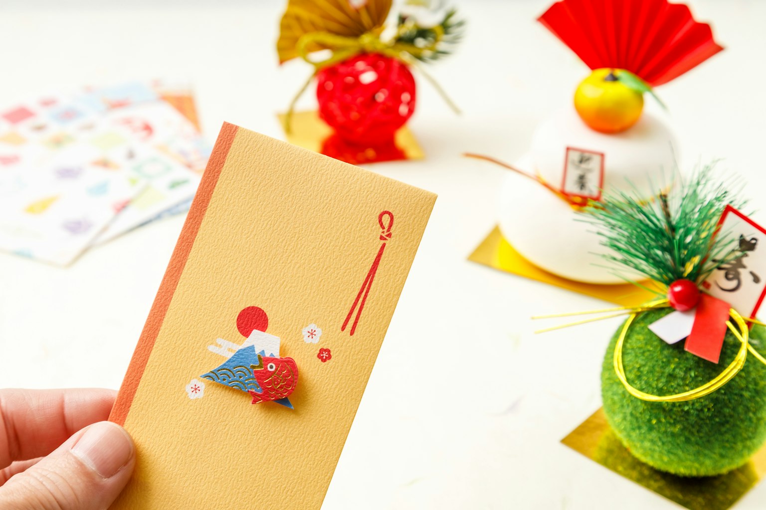 Une main tenant une enveloppe jaune avec des décorations japonaises traditionnelles en arrière-plan