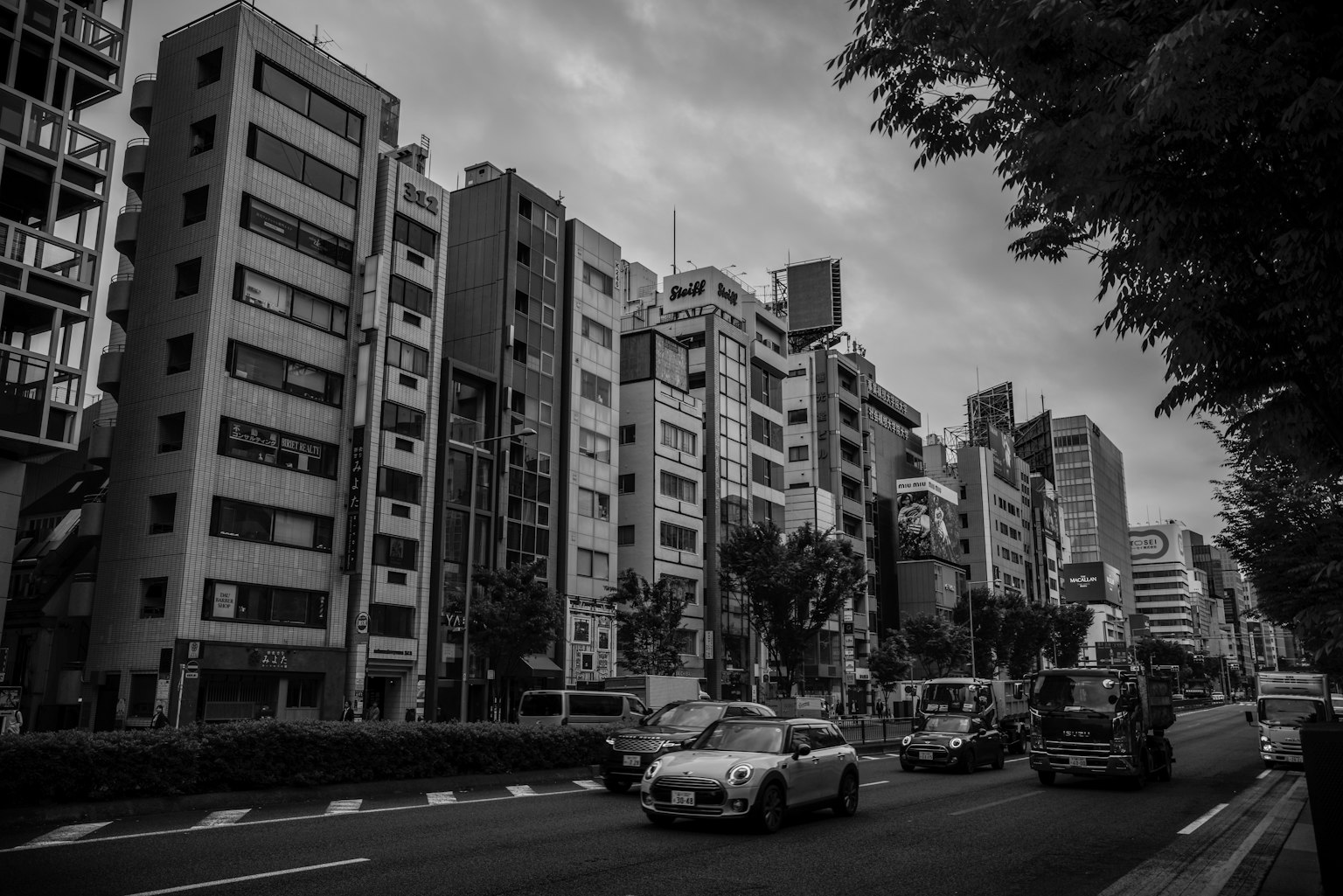 Cảnh đô thị đen trắng với tòa nhà cao và phương tiện trên đường
