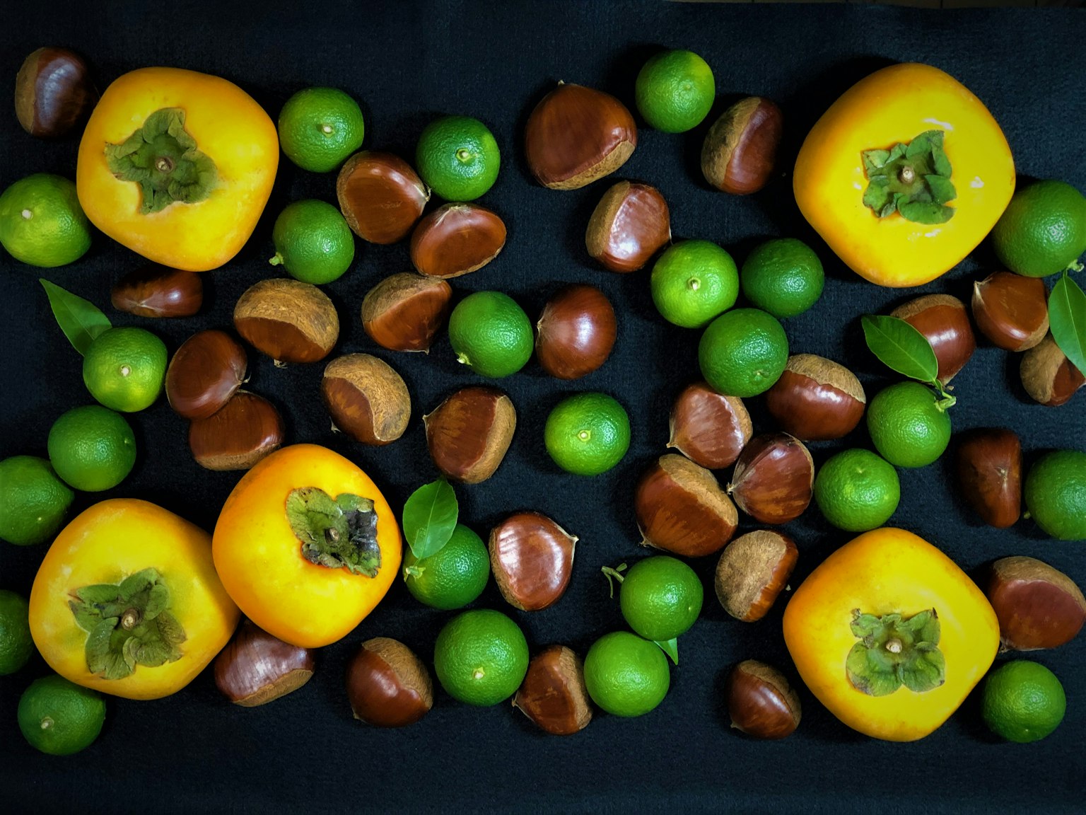 Disposizione di cachi e castagne su uno sfondo nero