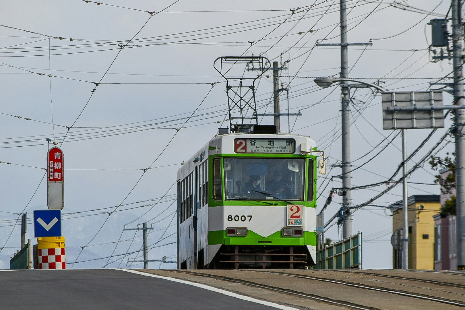 tram running through a street intersection with dense overhead wires