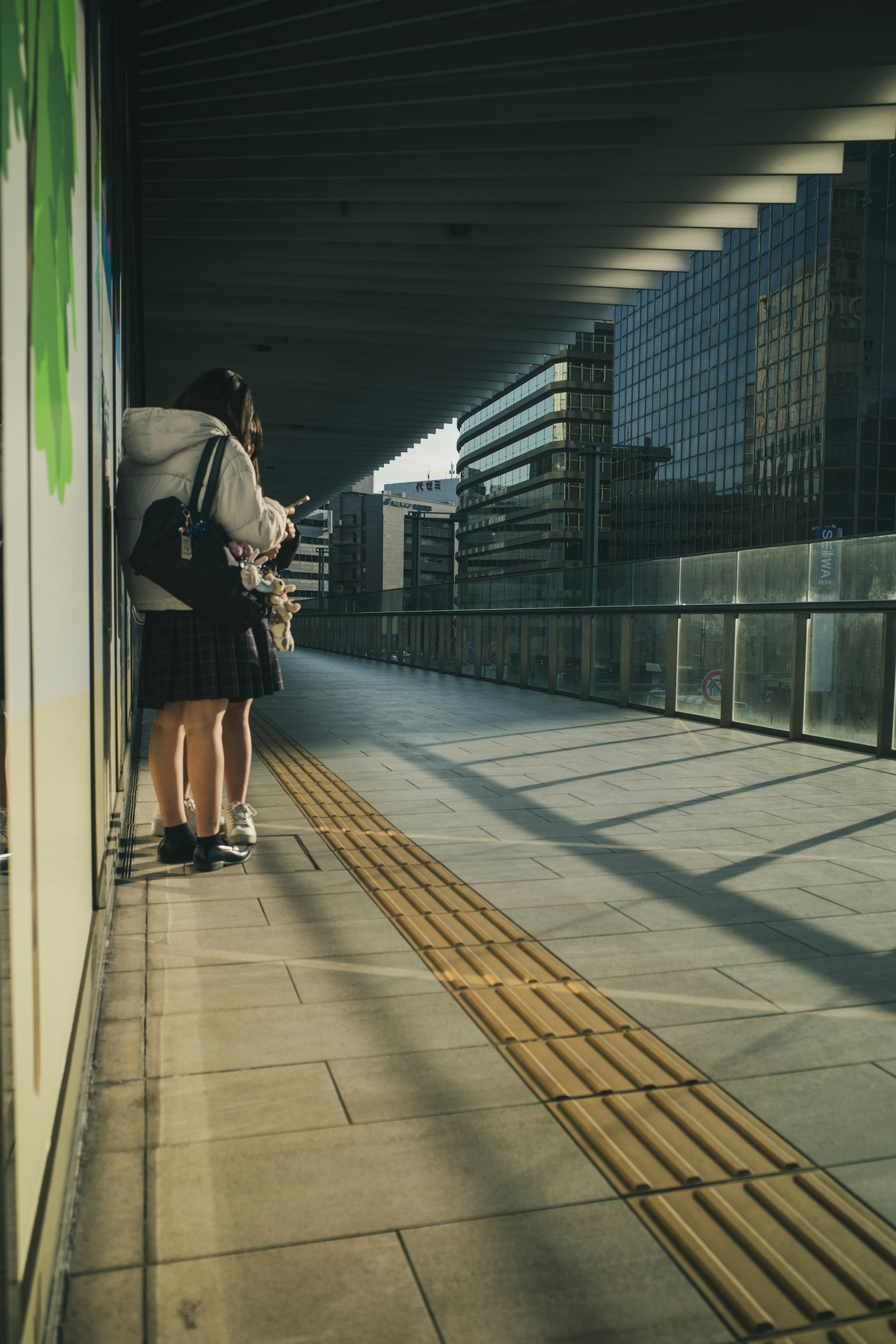 Back view of students in uniform standing on a city sidewalk