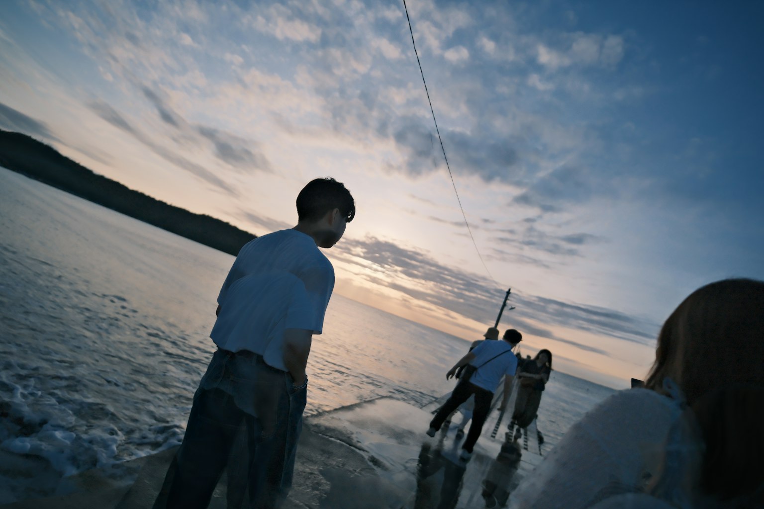 海辺で夕暮れを楽しむ人々のシルエット